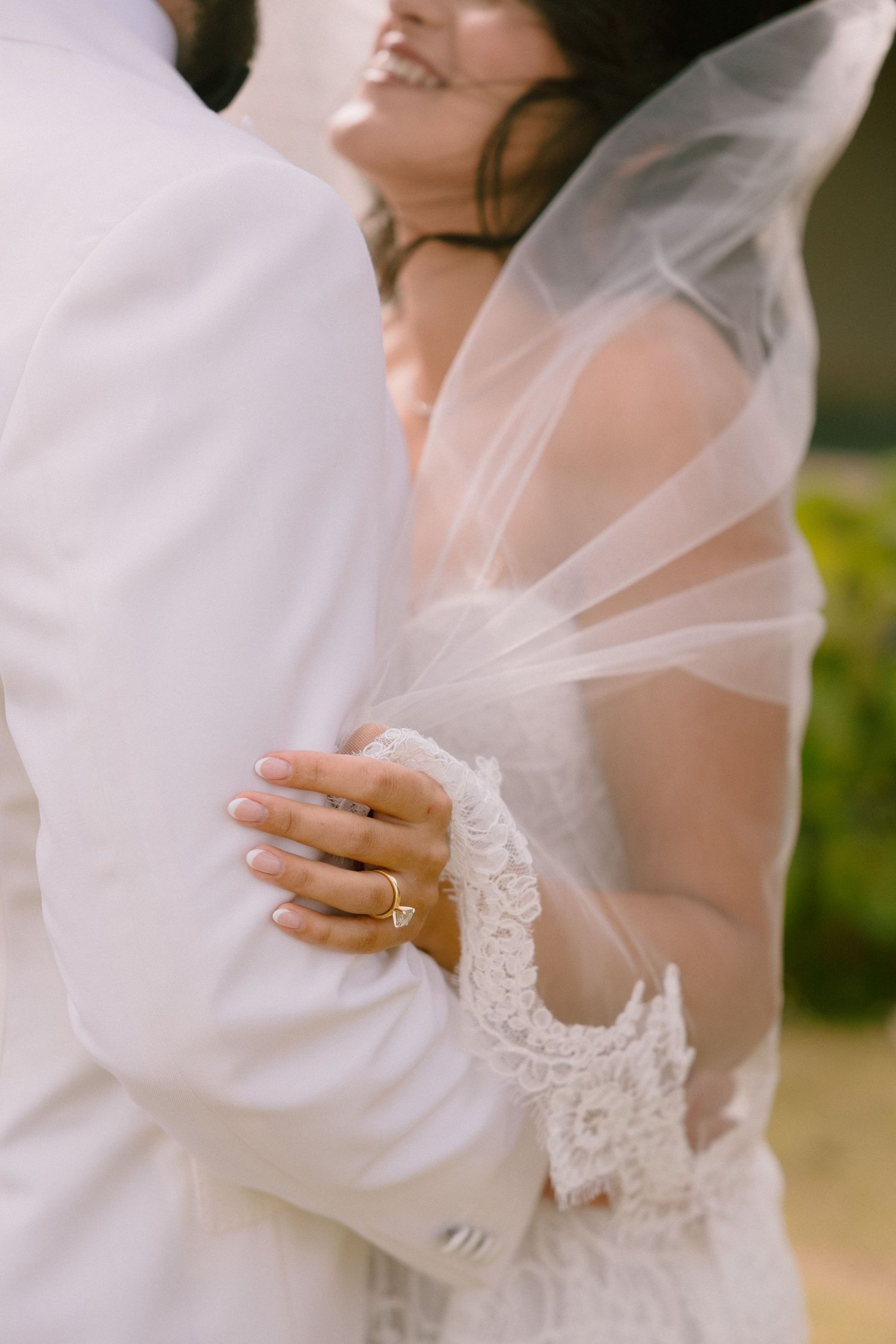 Close-up detail shots of a bride's white lace wedding dress and veil in soft natural lighting.