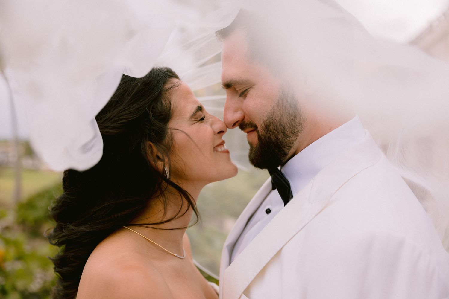 A romantic couple in wedding attire share intimate moments outdoors during a photo session.
