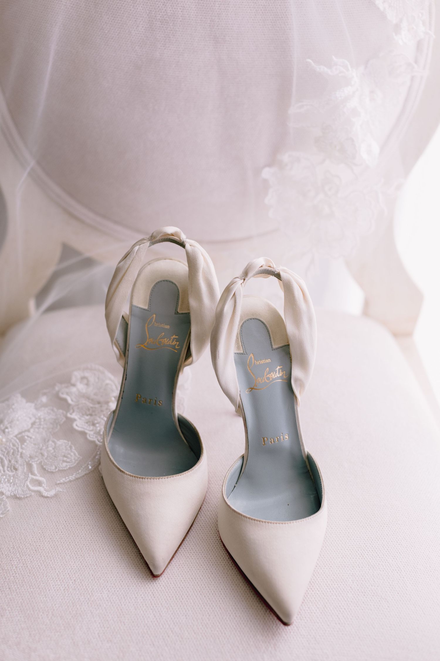 Elegant white satin bridal heels with pointed toes and slingback straps displayed against a light background.