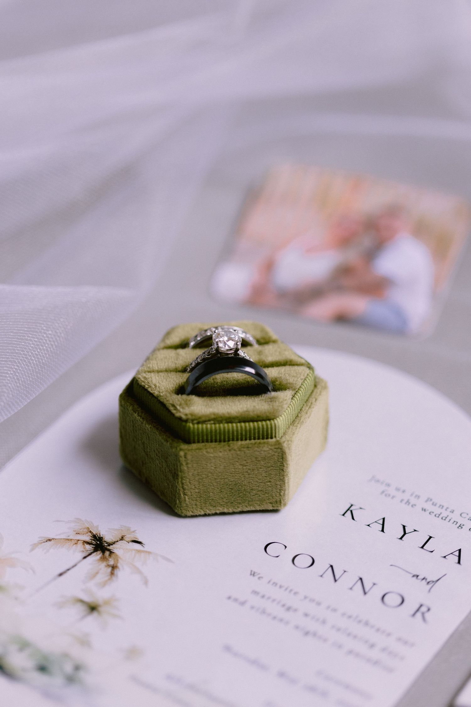 Diamond engagement ring in green velvet hexagon box on Kayla and Connor wedding invitation with couple photo.