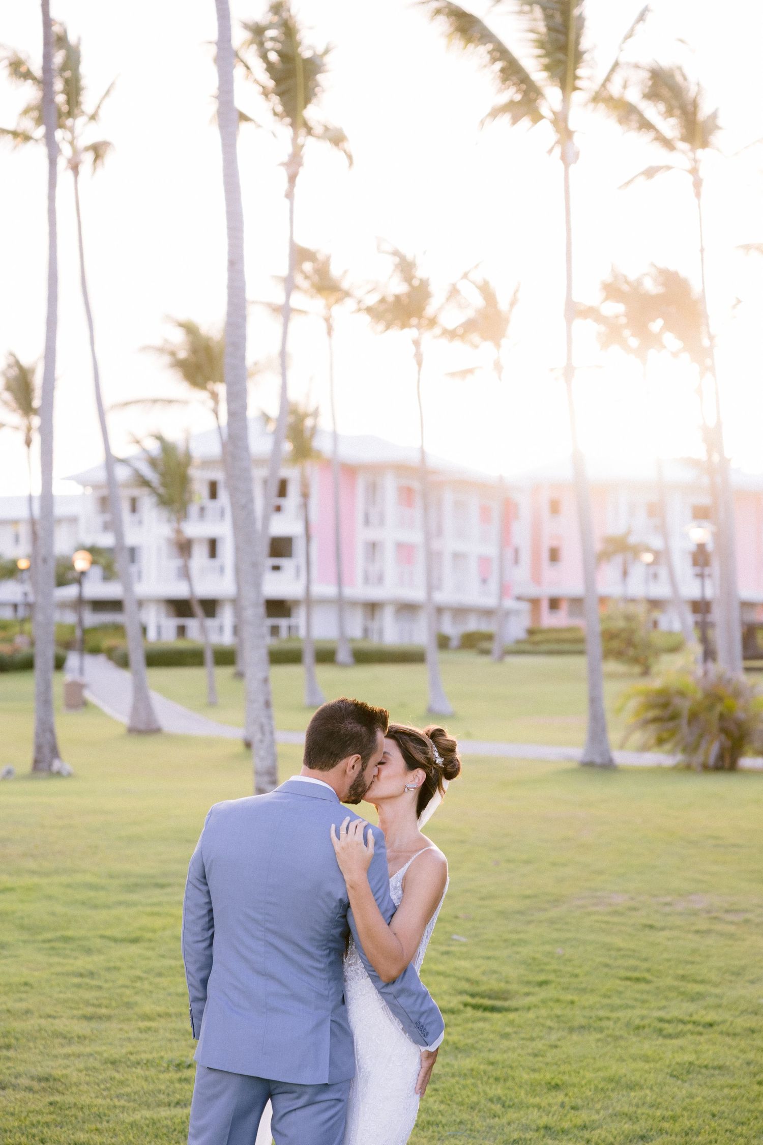Intimate moment between newlyweds surrounded by palm trees at sunset.