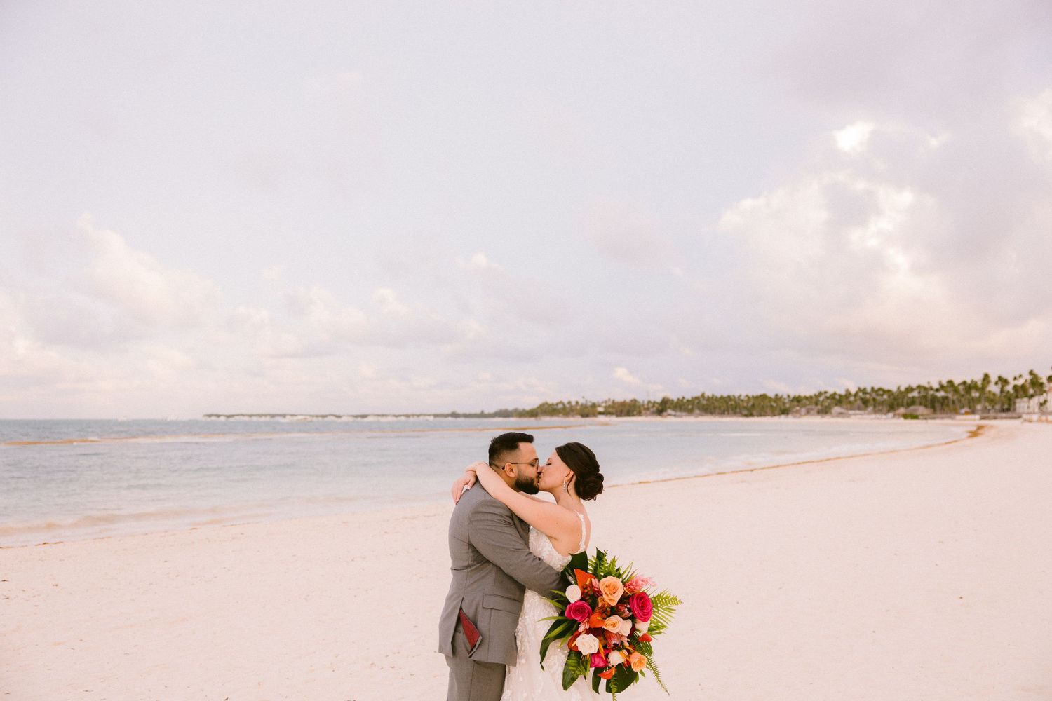 A couple shares a romantic moment during their beach wedding ceremony at sunset.
