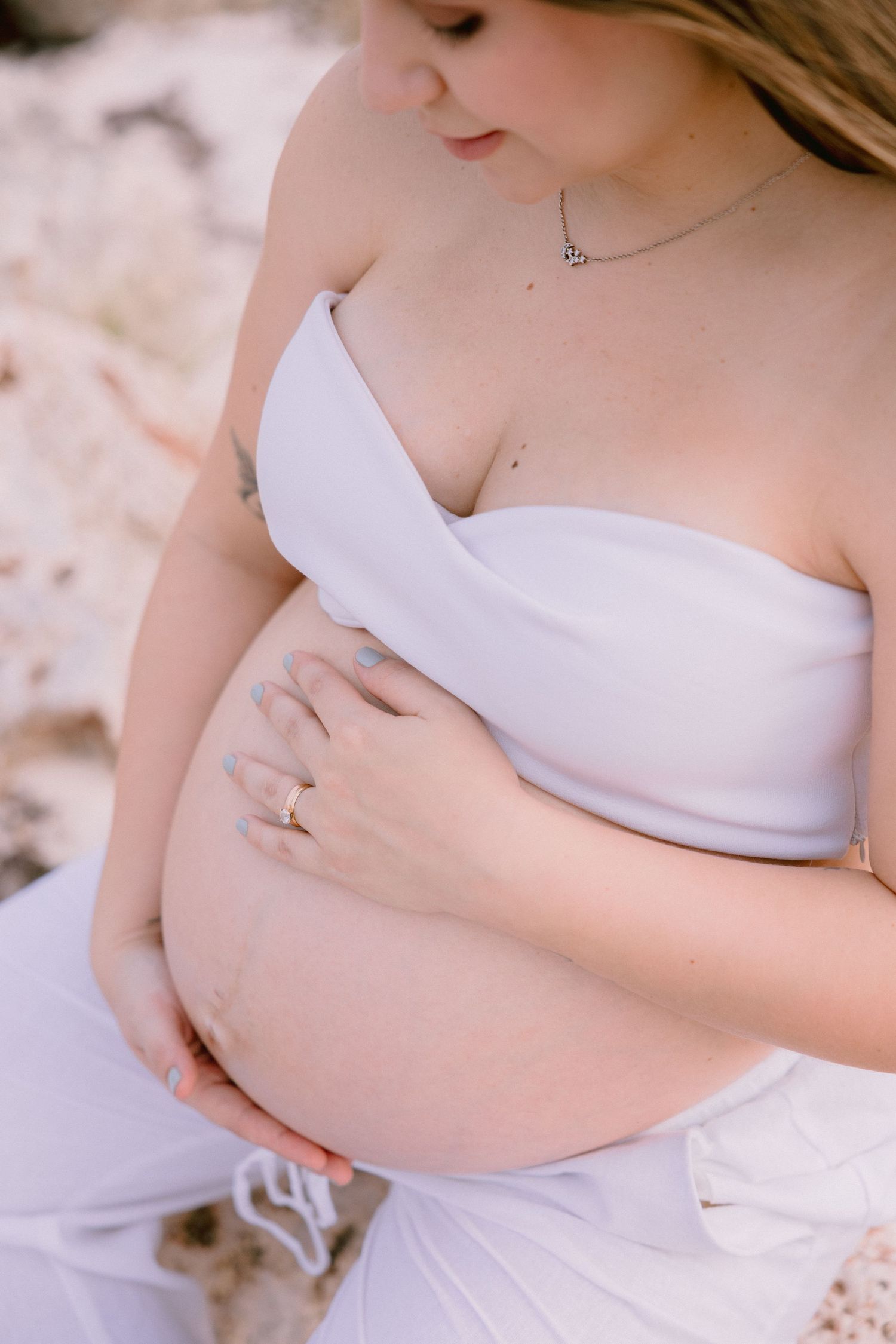 A maternity photo series showing tender moments of an expectant mother in a white dress against a soft background.