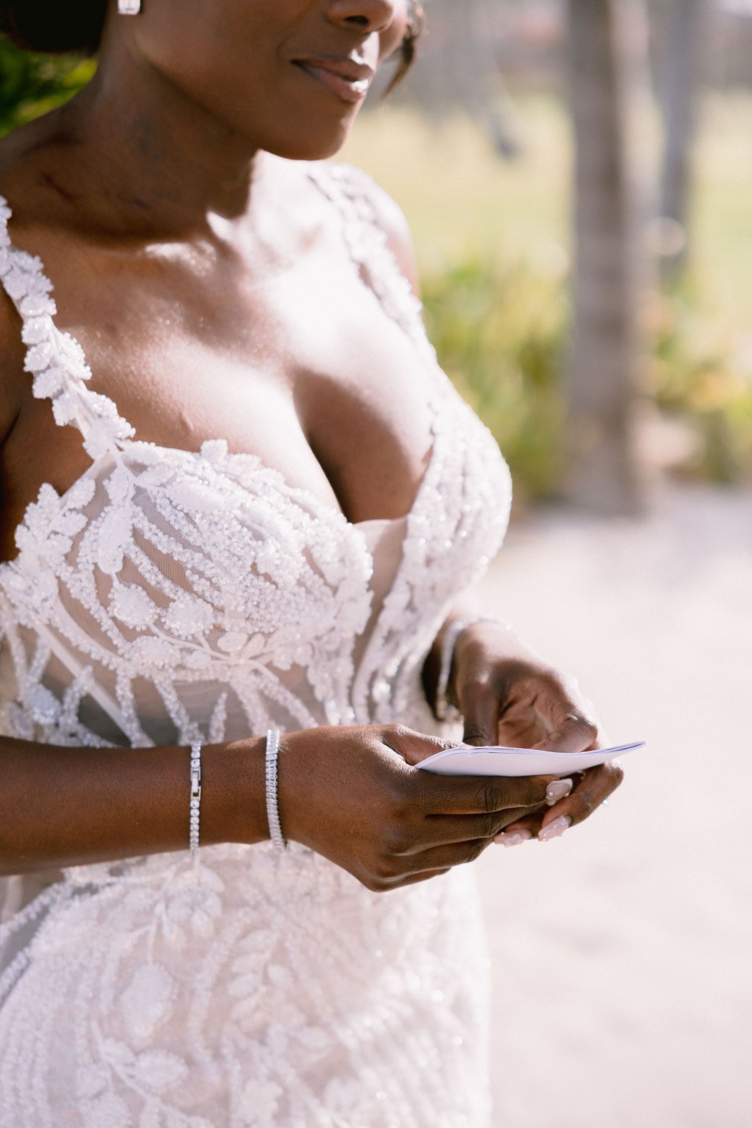 Close-up view of hands holding a mobile phone while wearing an elegant white lace wedding dress.