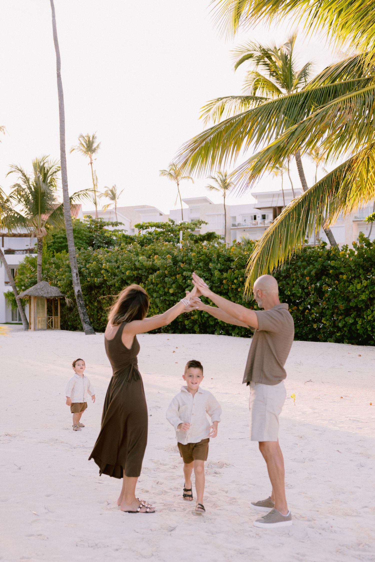 A sequence of photos showing people dancing and playing on a tropical beach with palm trees at sunset.