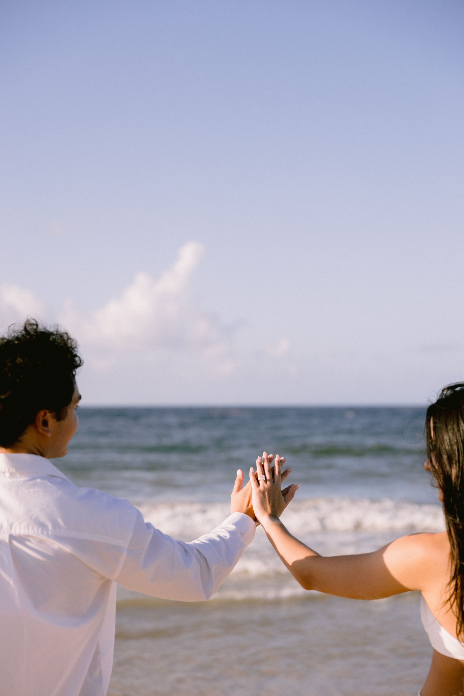 Silhouetted figures dancing together on a beach with ocean waves in the background.