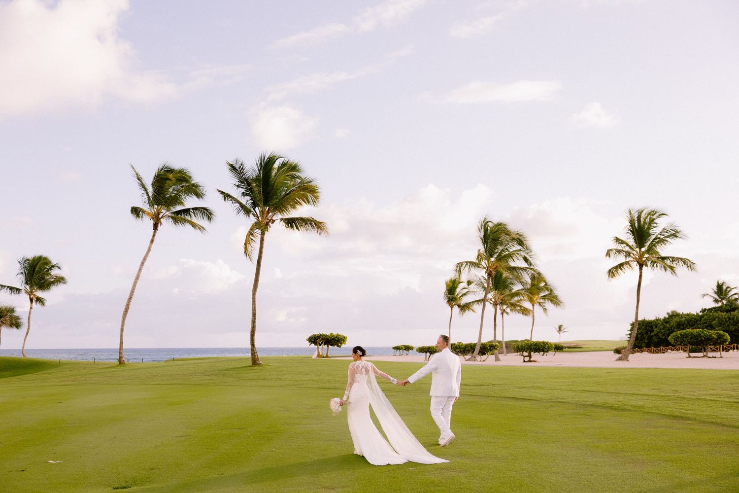 Panoramic sequence of a tropical beach wedding ceremony setup with white fabric decor and palm trees swaying in the breeze.