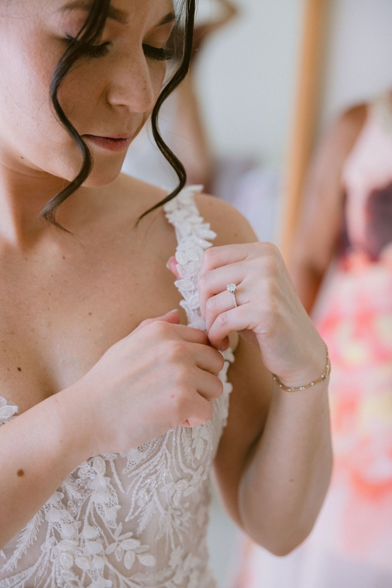 Close-up details of a bride in an elegant white lace wedding dress with delicate embroidery patterns.