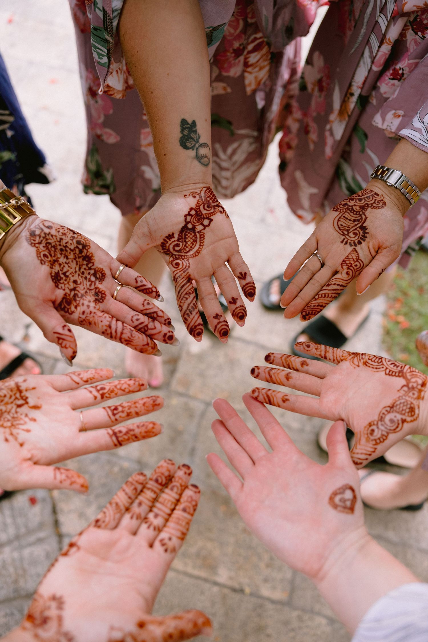 Multiple hands adorned with intricate henna designs are displayed together in a celebratory gathering.