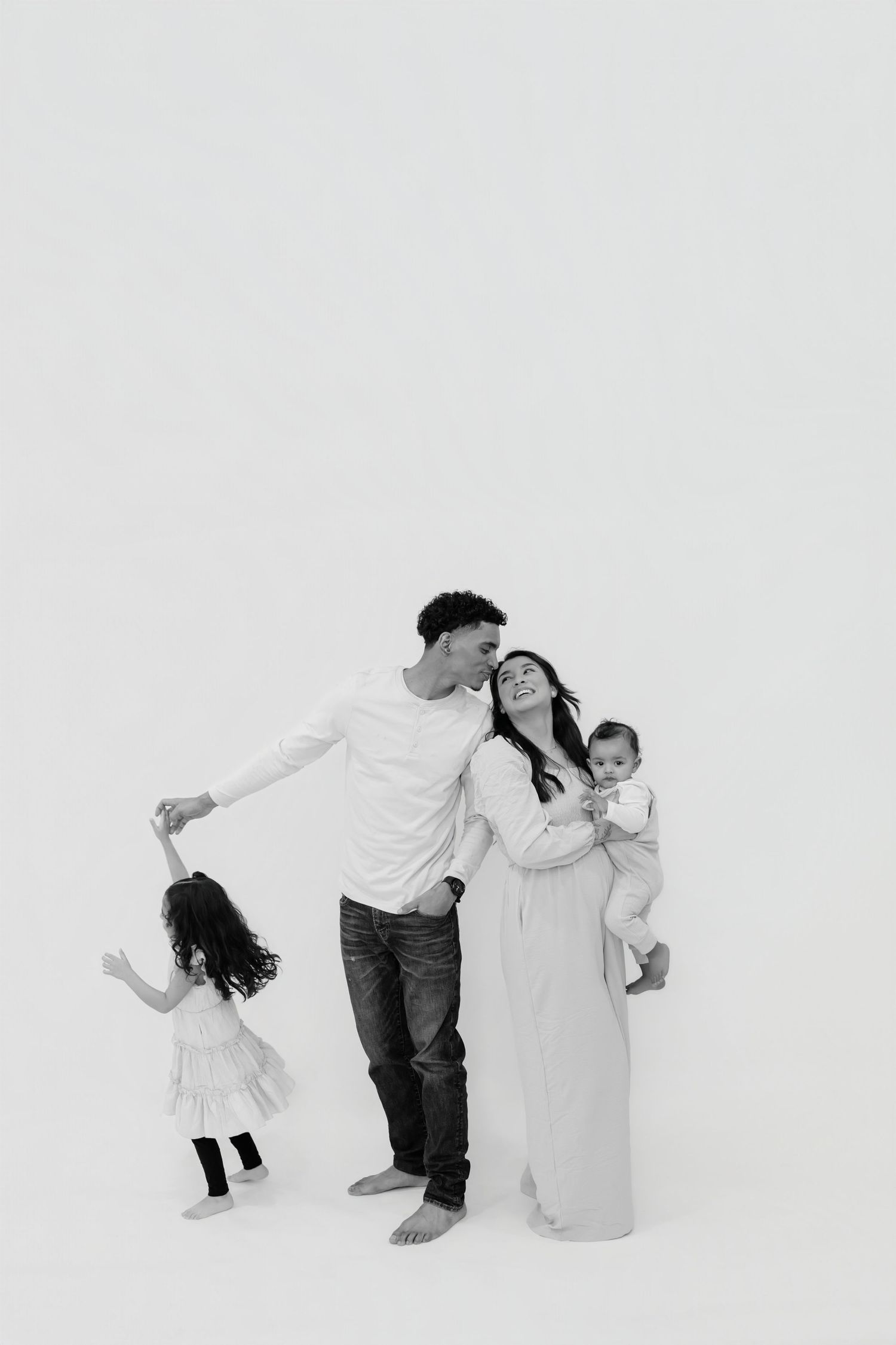A black and white photo sequence showing a playful dance movement between two people in white outfits against a plain backdrop.