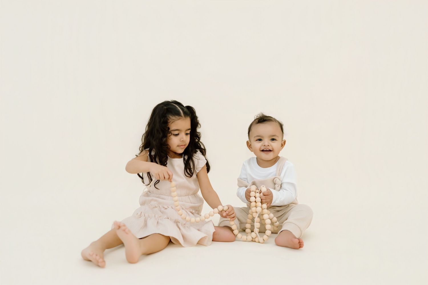 Five adorable babies wearing white outfits lie on a white background in a collage-style photo arrangement.