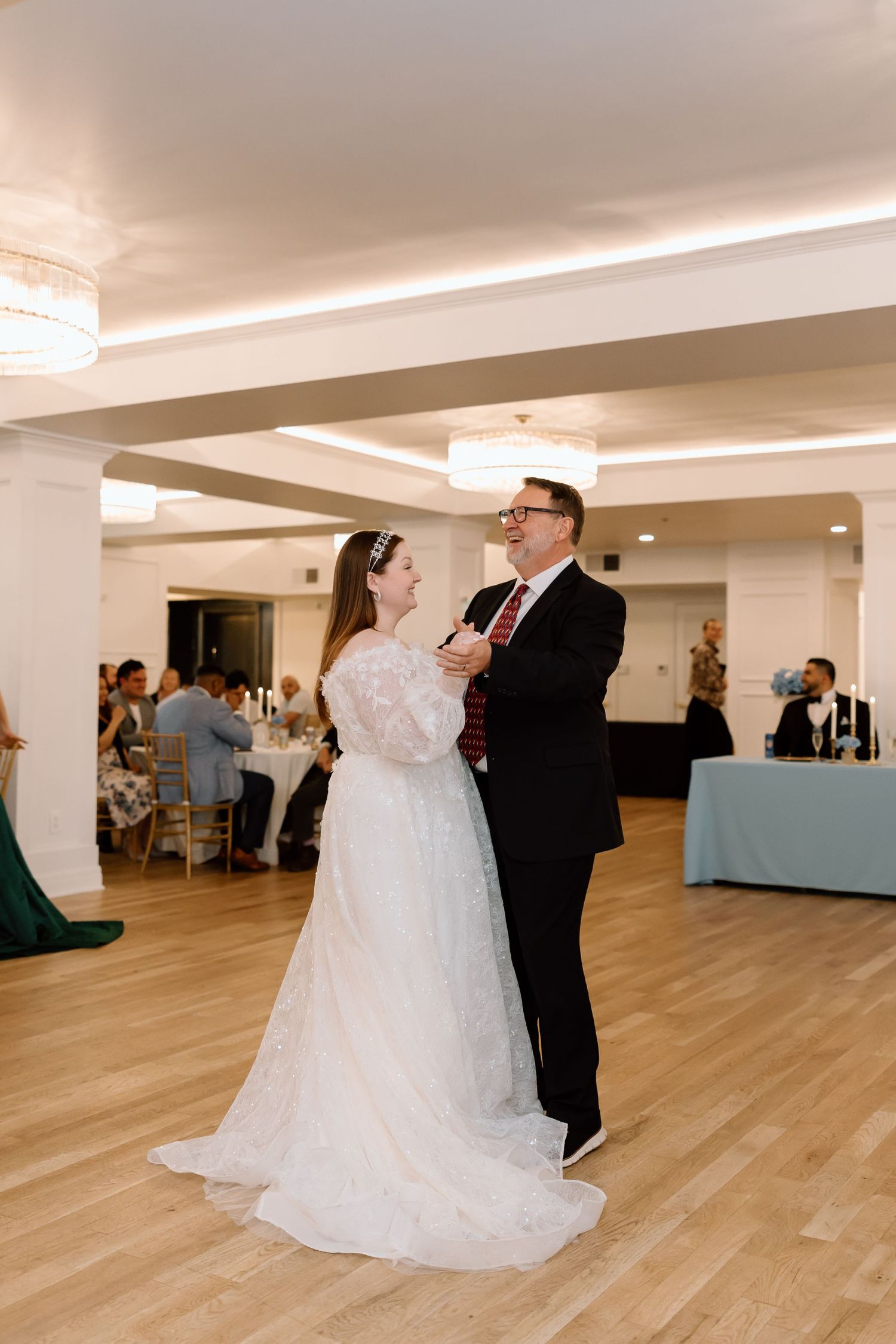 Bride and groom share their first dance in an elegant wedding reception hall with warm lighting.