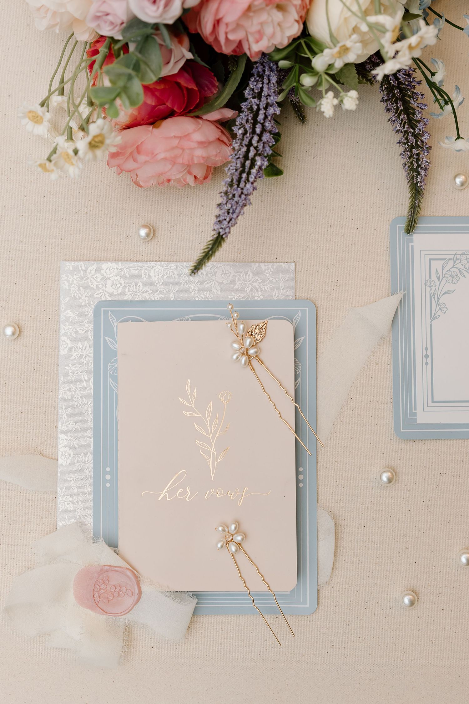 Elegant wedding stationery layout with soft pink roses, lavender sprigs, and light blue frames on cream background.