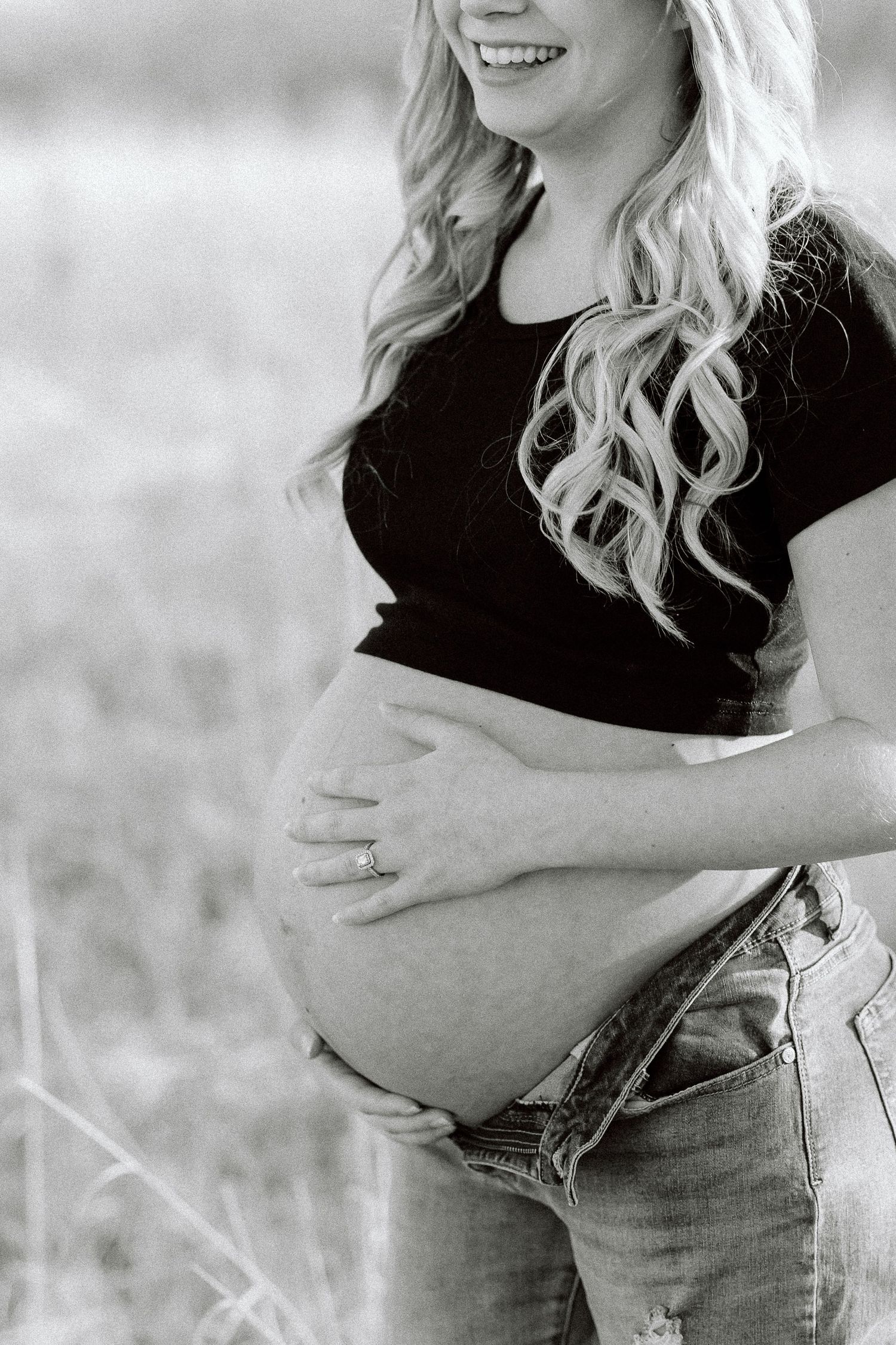 Black and white maternity photography series showing close-up shots of a pregnant belly in casual clothing.