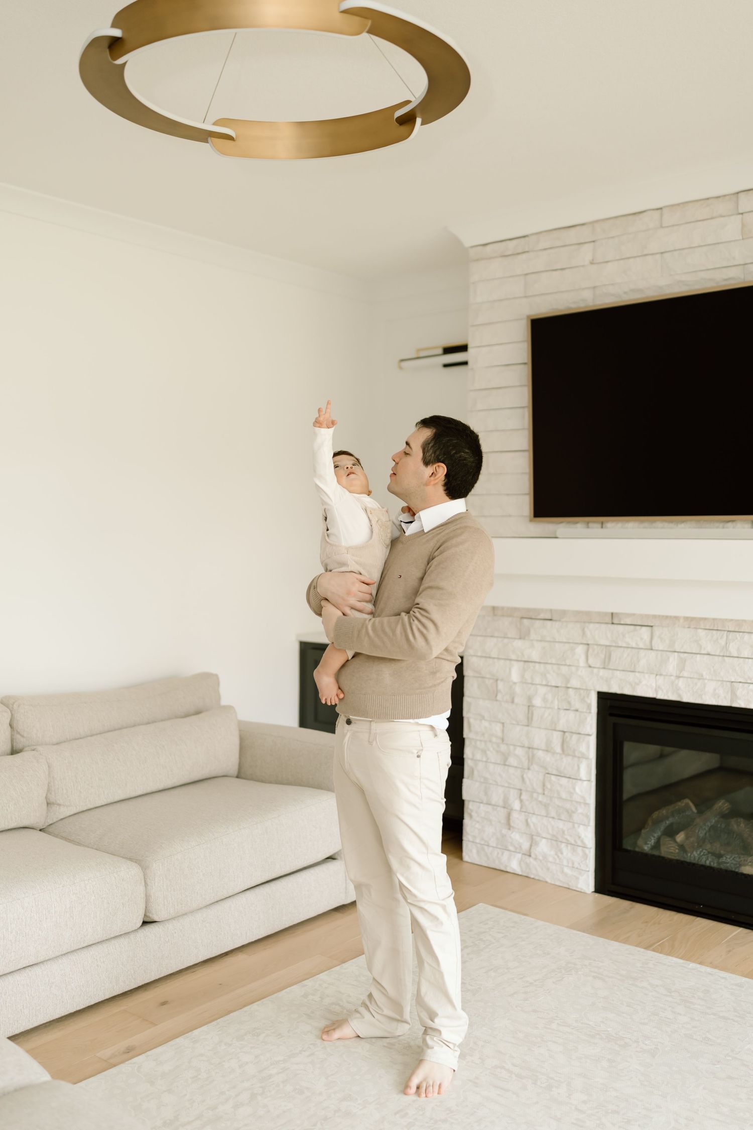 A minimalist white living room interior with a person stretching in workout clothes against a white brick wall.