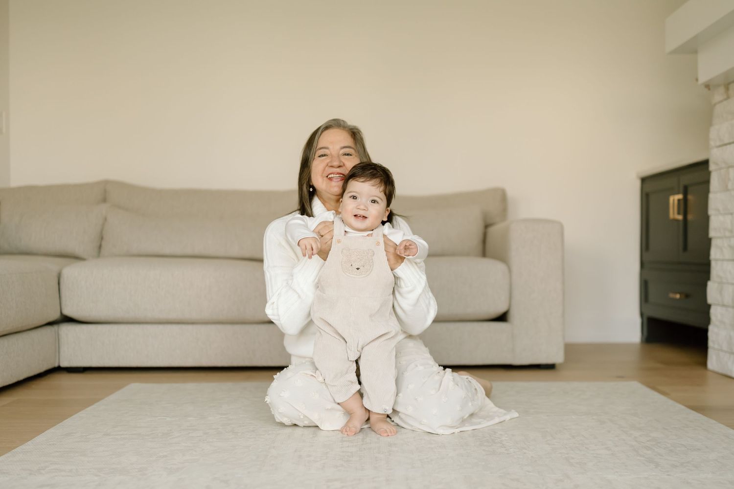 A series of photos showing a baby sitting and playing on a light gray couch in a modern living room.