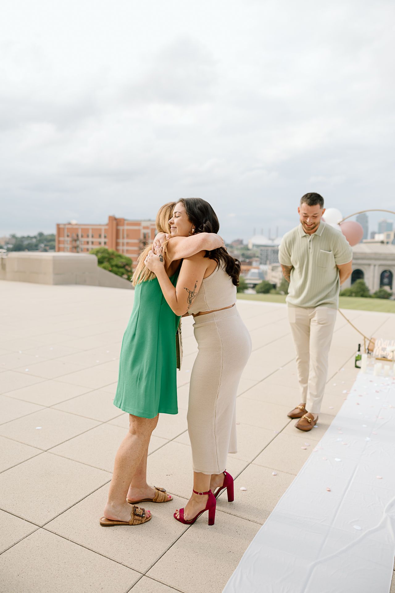 Three sequential photos showing a couple embracing on a light-colored stone terrace with city buildings in background.