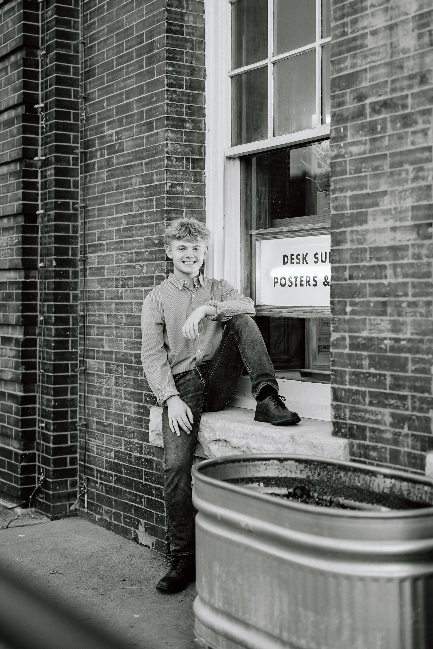 A sequence of black and white photos showing someone sliding down a curved railing outside a brick building.