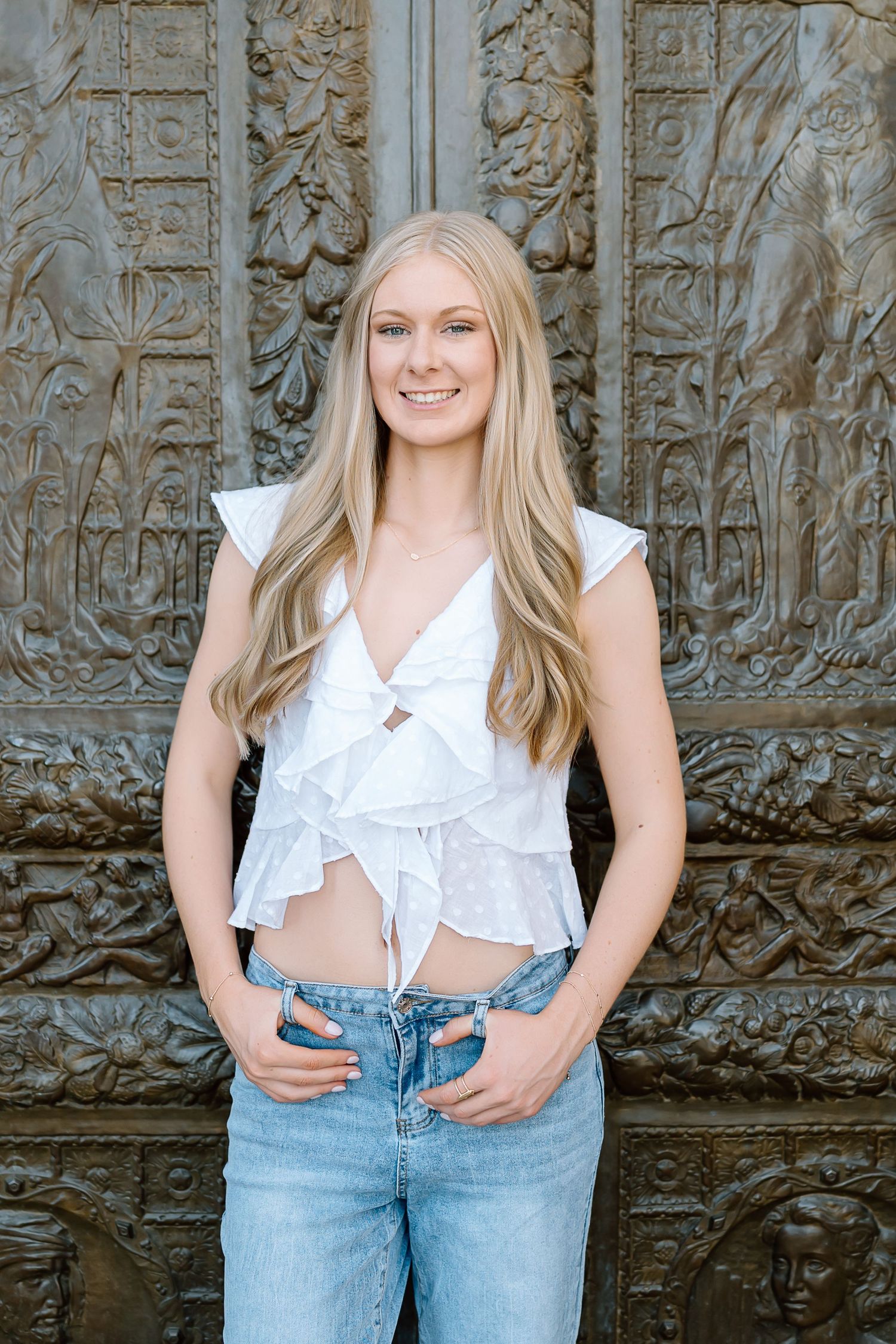 A series of four fashion portraits showing a casual outfit with light denim jeans and a white top against a textured wall.