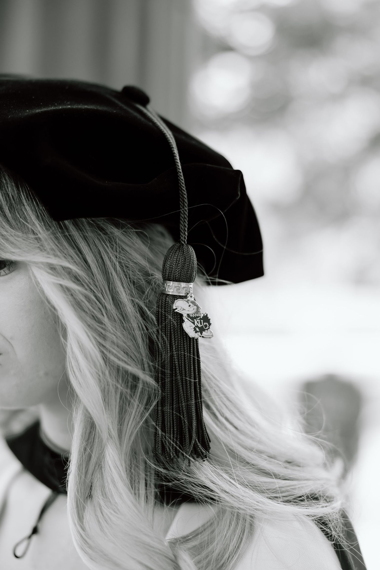 Black and white photo of blonde hair flowing from under a dark beret with decorative pins attached.