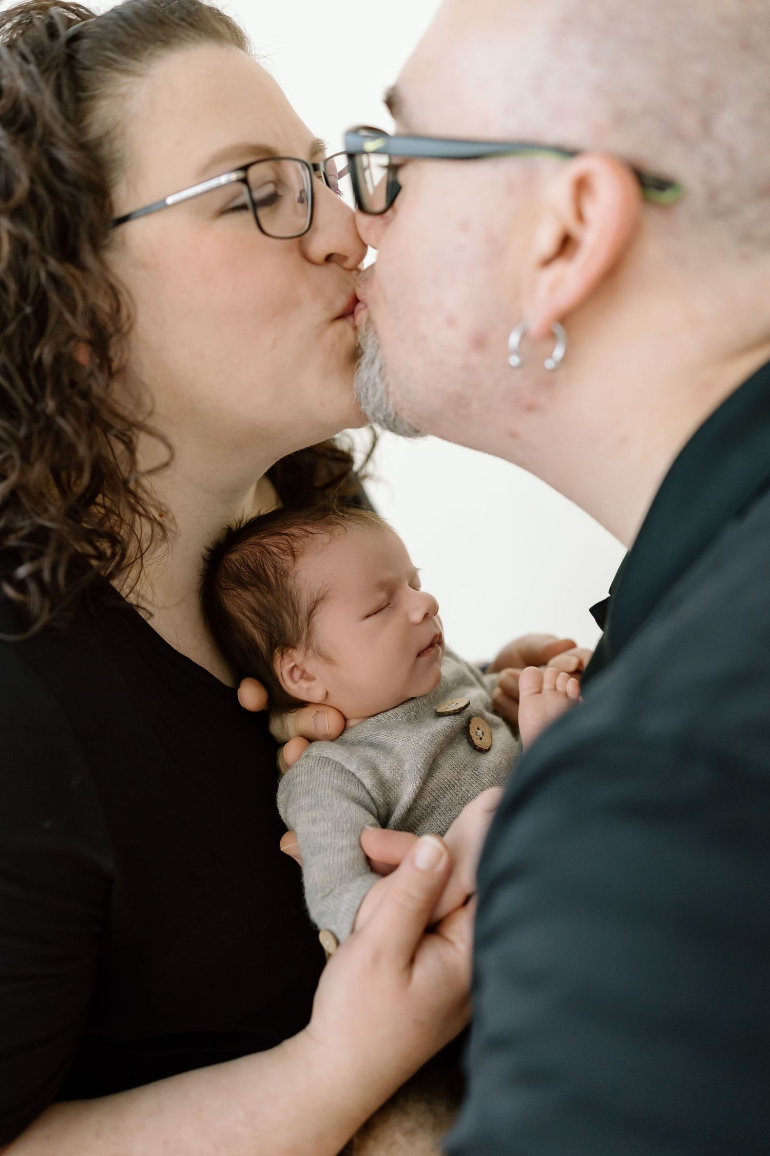 A tender series of intimate family moments showing parents bonding with their newborn baby in soft natural light.