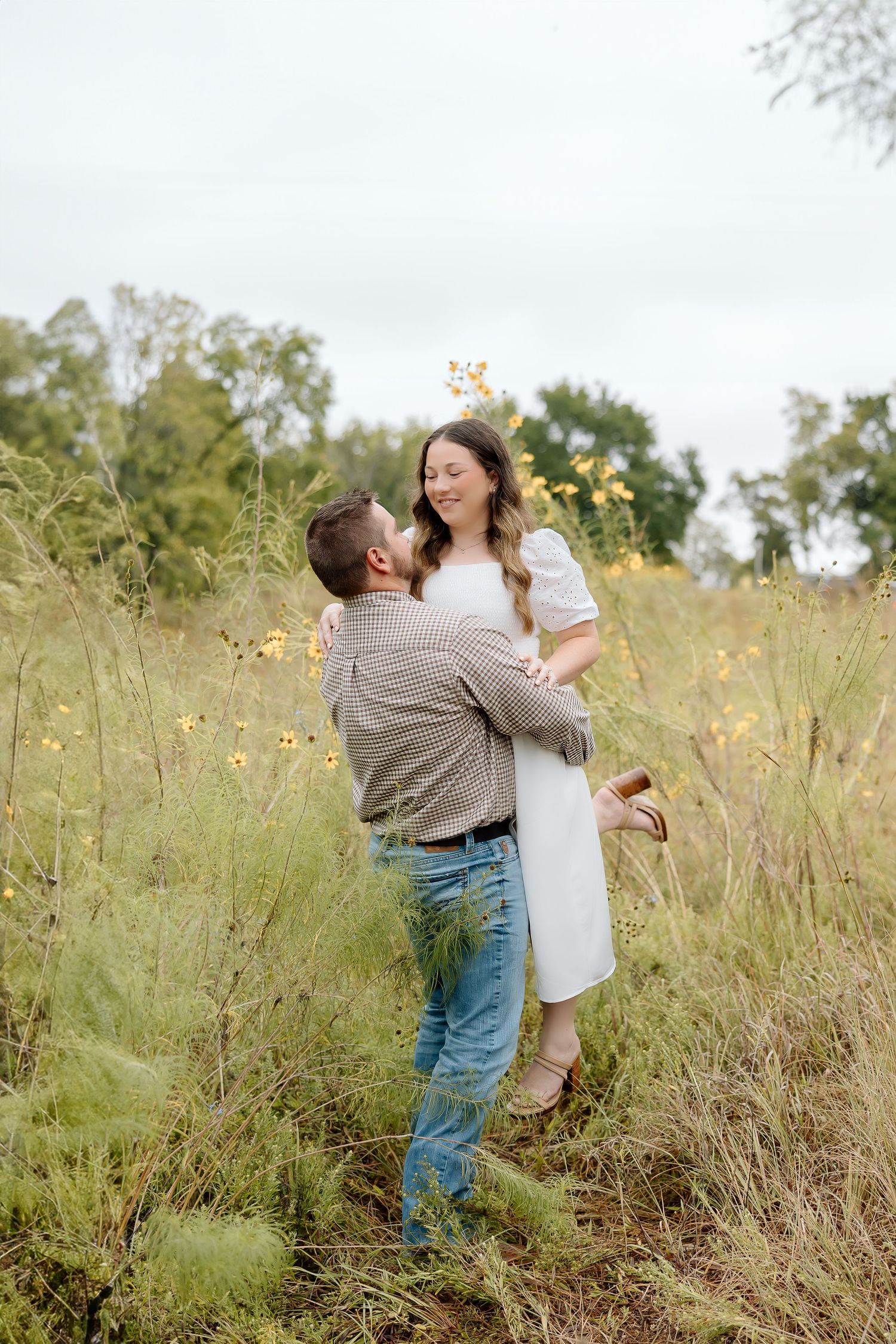 A joyful couple shares a playful moment as they embrace in a wildflower meadow.