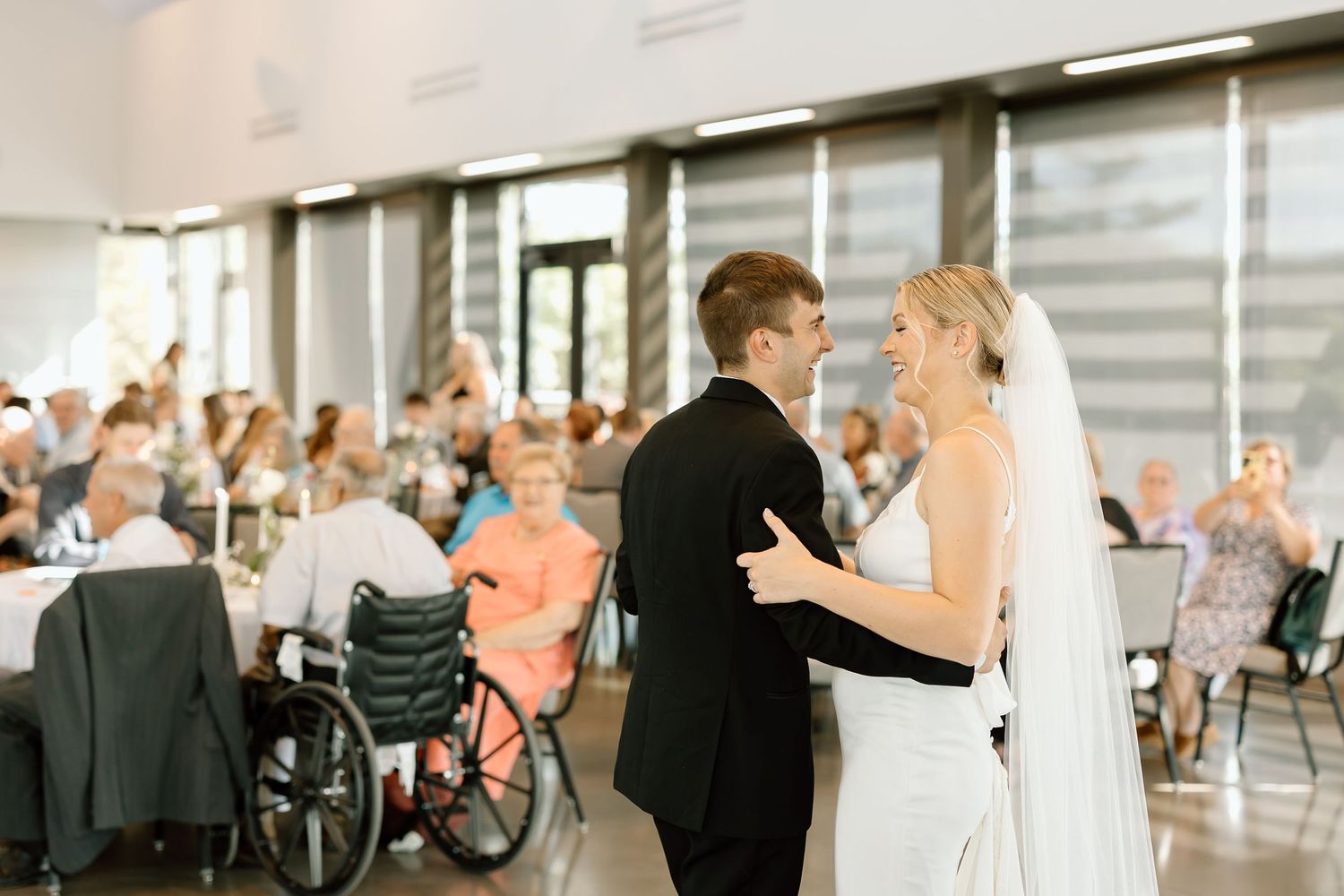 Elegant wedding reception venue with guests socializing and mingling in a bright modern space.