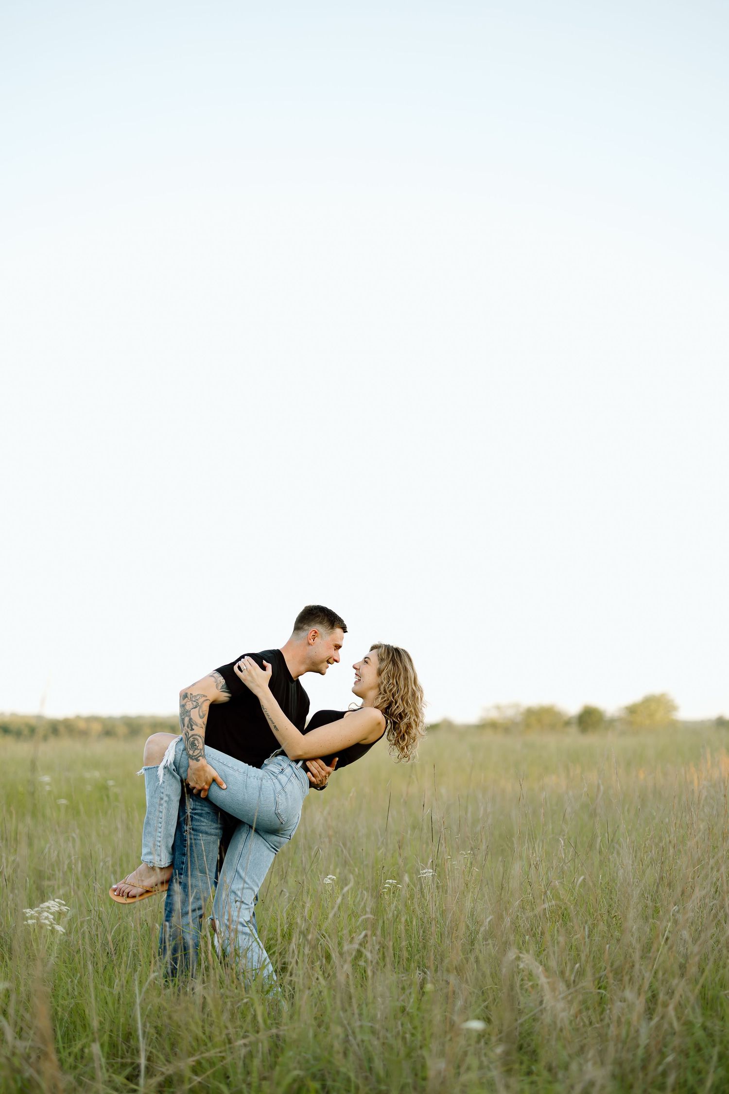 Couple embraces romantically in a golden meadow at sunset, creating a series of intimate poses.