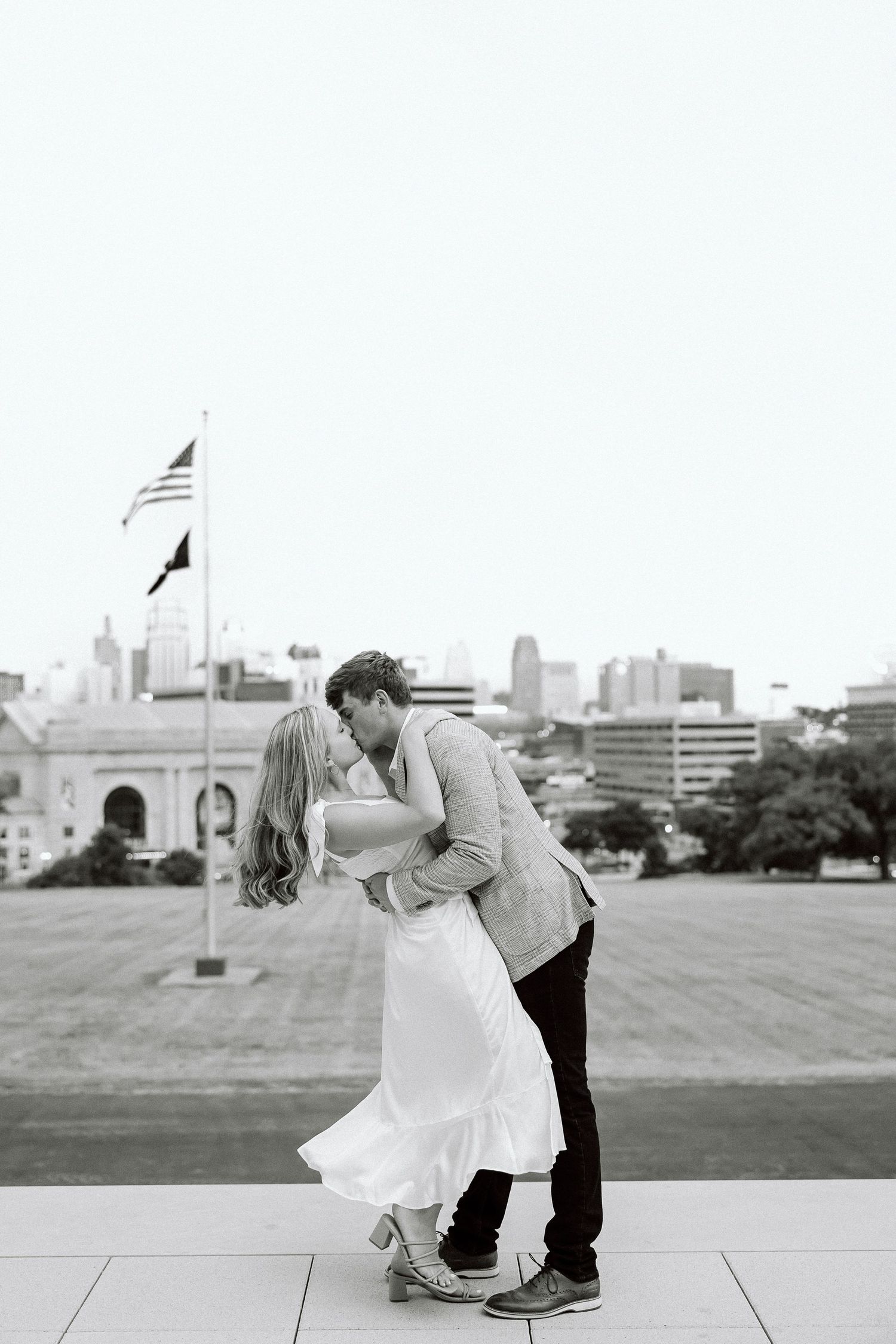 A romantic black and white photo sequence showing a couple dancing and dipping on a rooftop with a city skyline view.