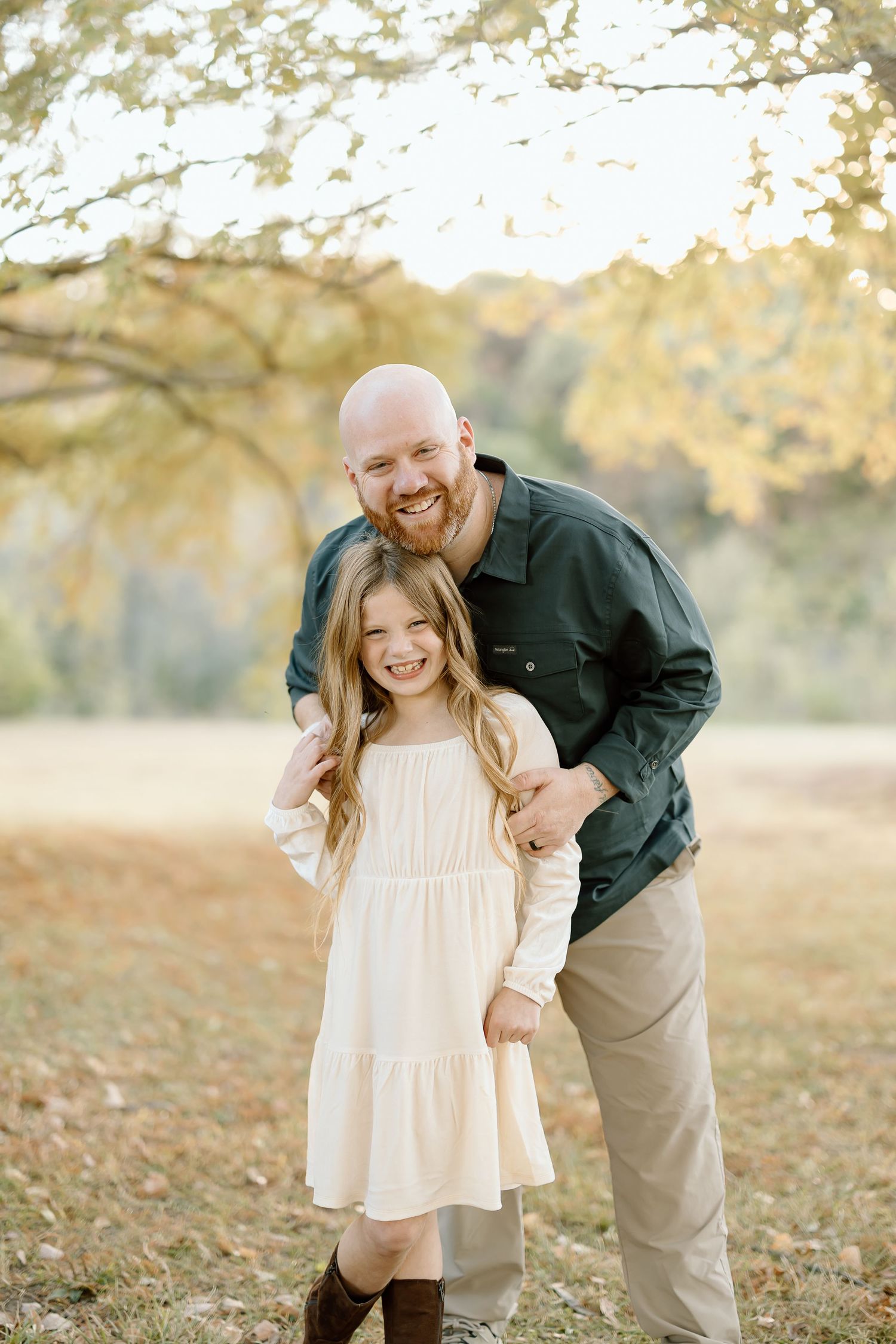 A parent and child share joyful moments together during a golden hour photo session in a fall outdoor setting.