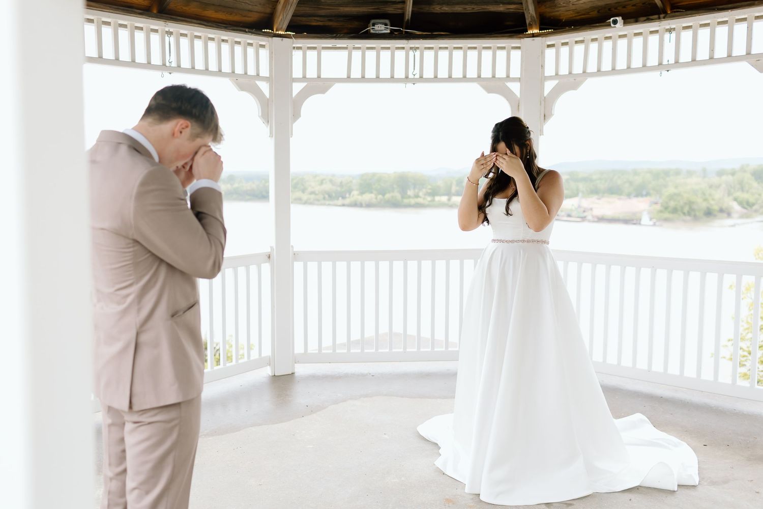 A couple shares a first look moment in a white gazebo overlooking scenic views during their wedding day.