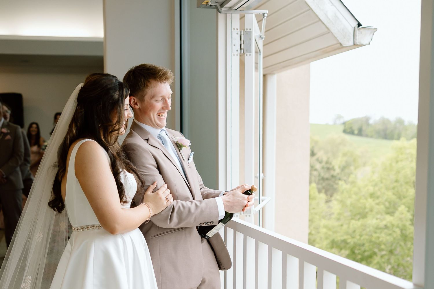 A couple stands together by a bright window in their home during a lifestyle photography session.