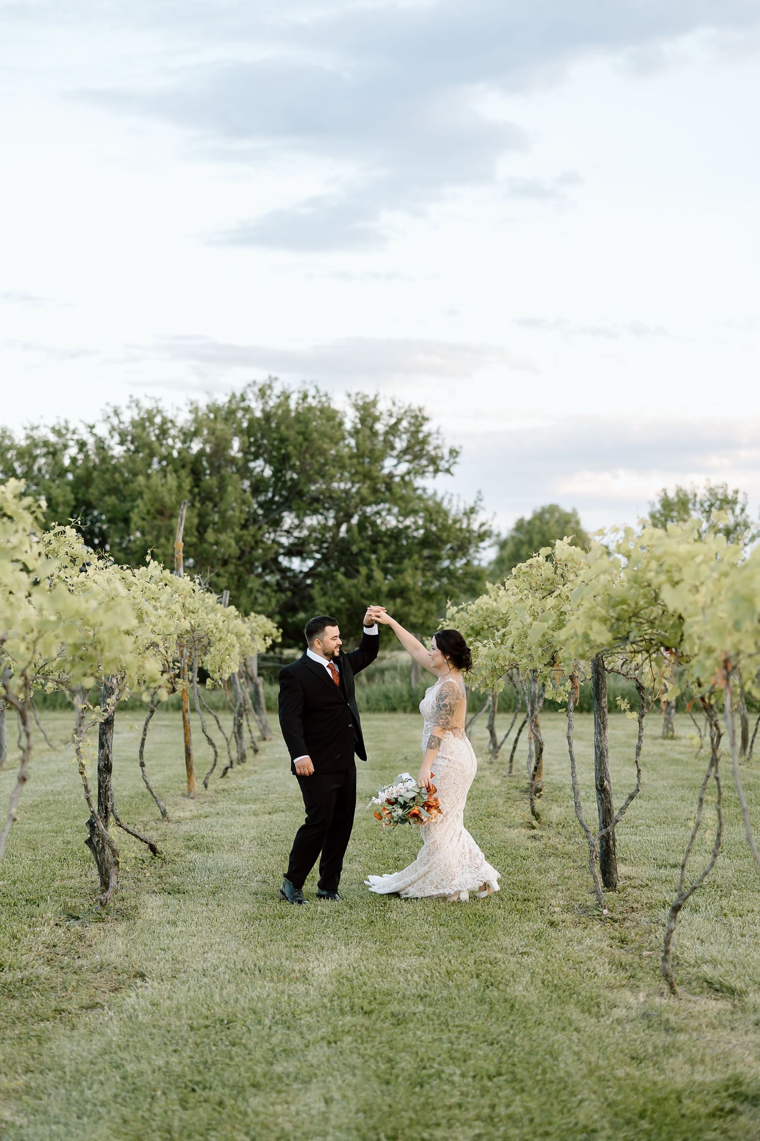 A couple dances together in a scenic vineyard setting on their wedding day.