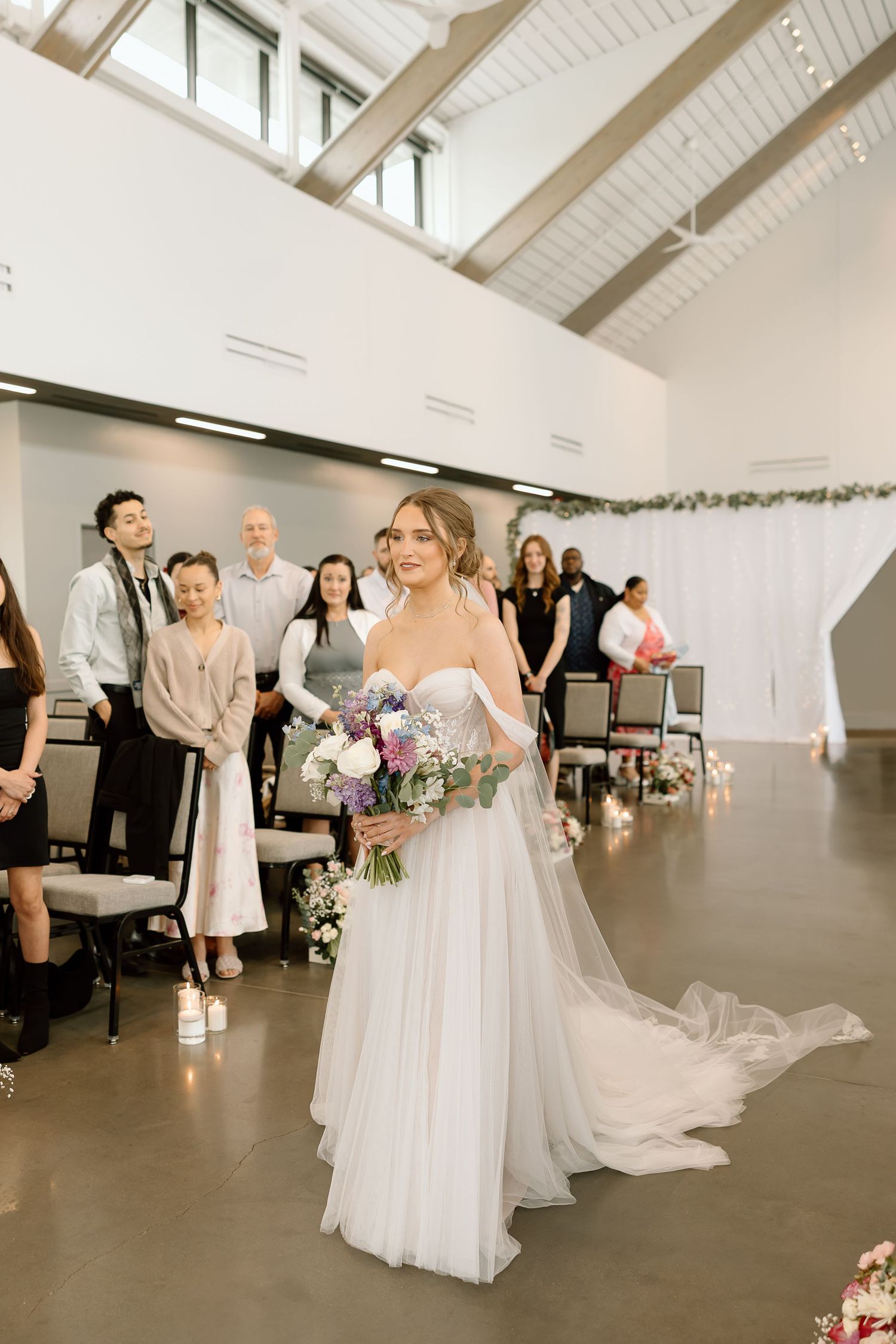 Modern indoor wedding ceremony with white vaulted ceiling and minimalist decor.