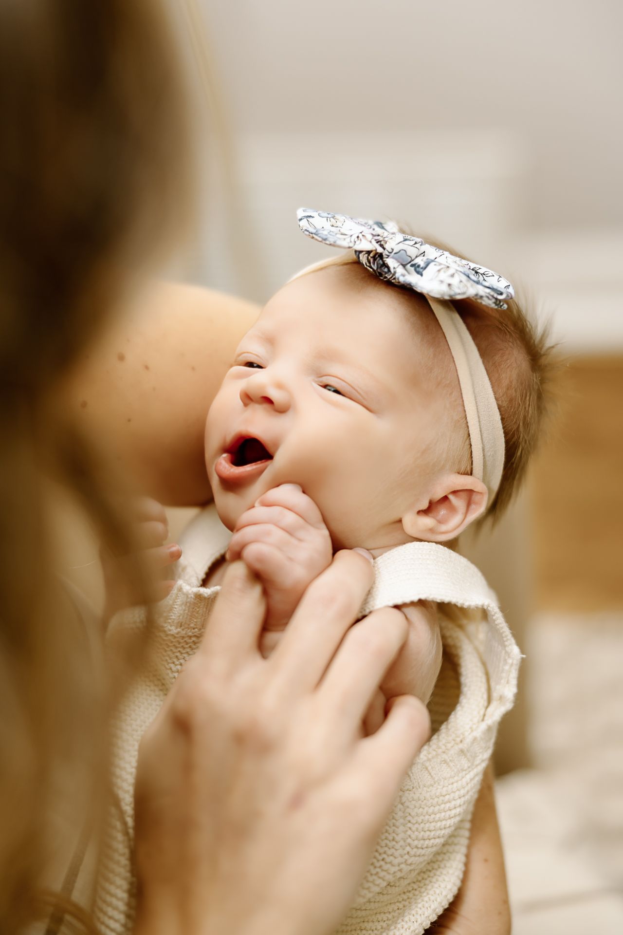 Happy baby wearing decorative headband smiles while being held.