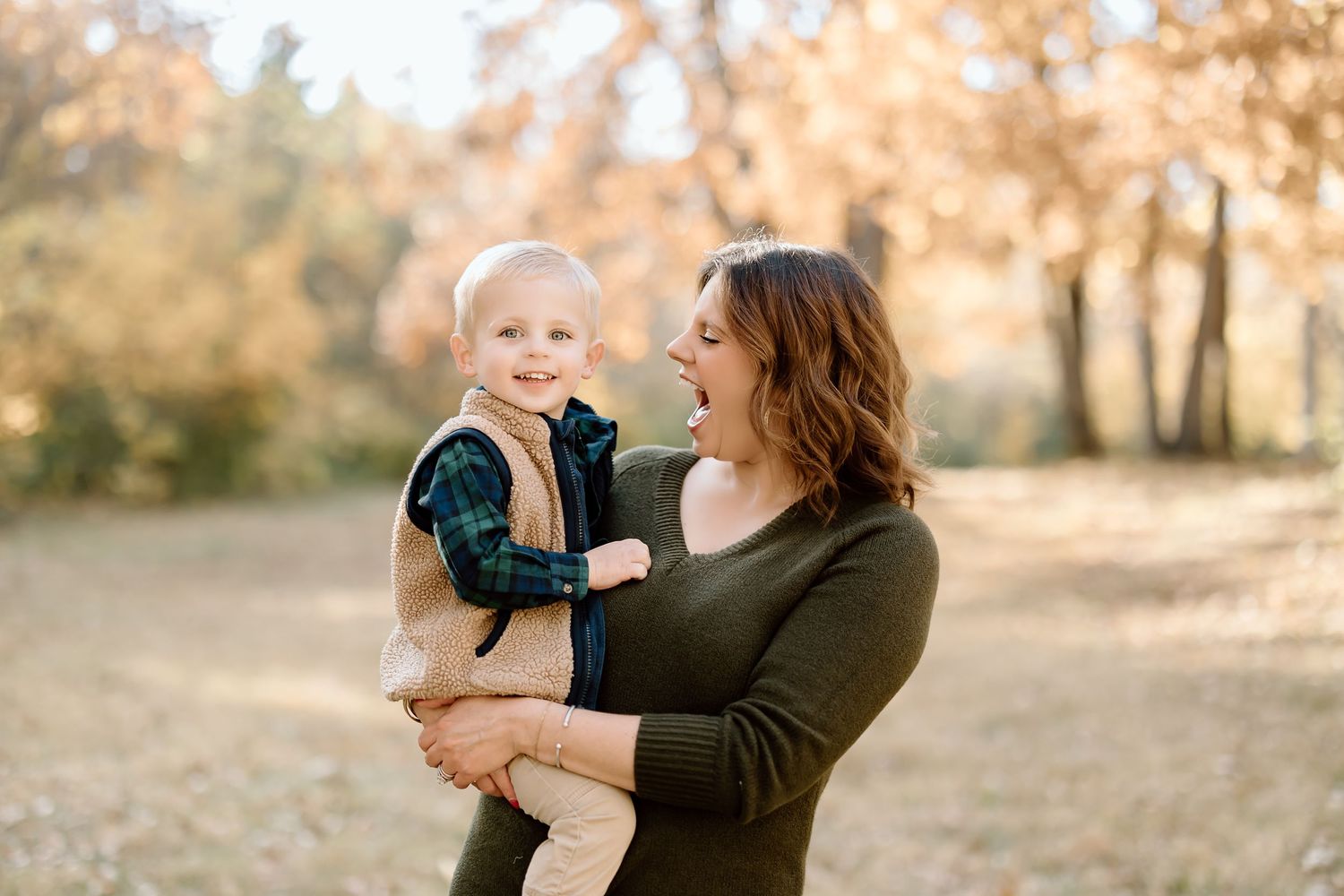 A candid moment shows a parent and child sharing laughter during an outdoor photo session.