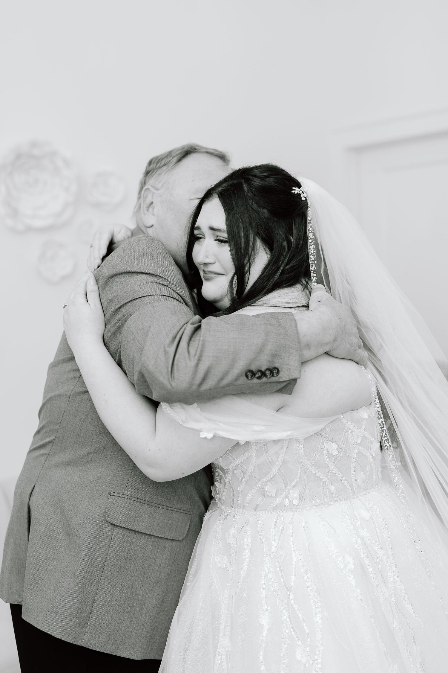 A series of black and white photos showing emotional embraces between a bride in a white dress and someone in a gray suit.
