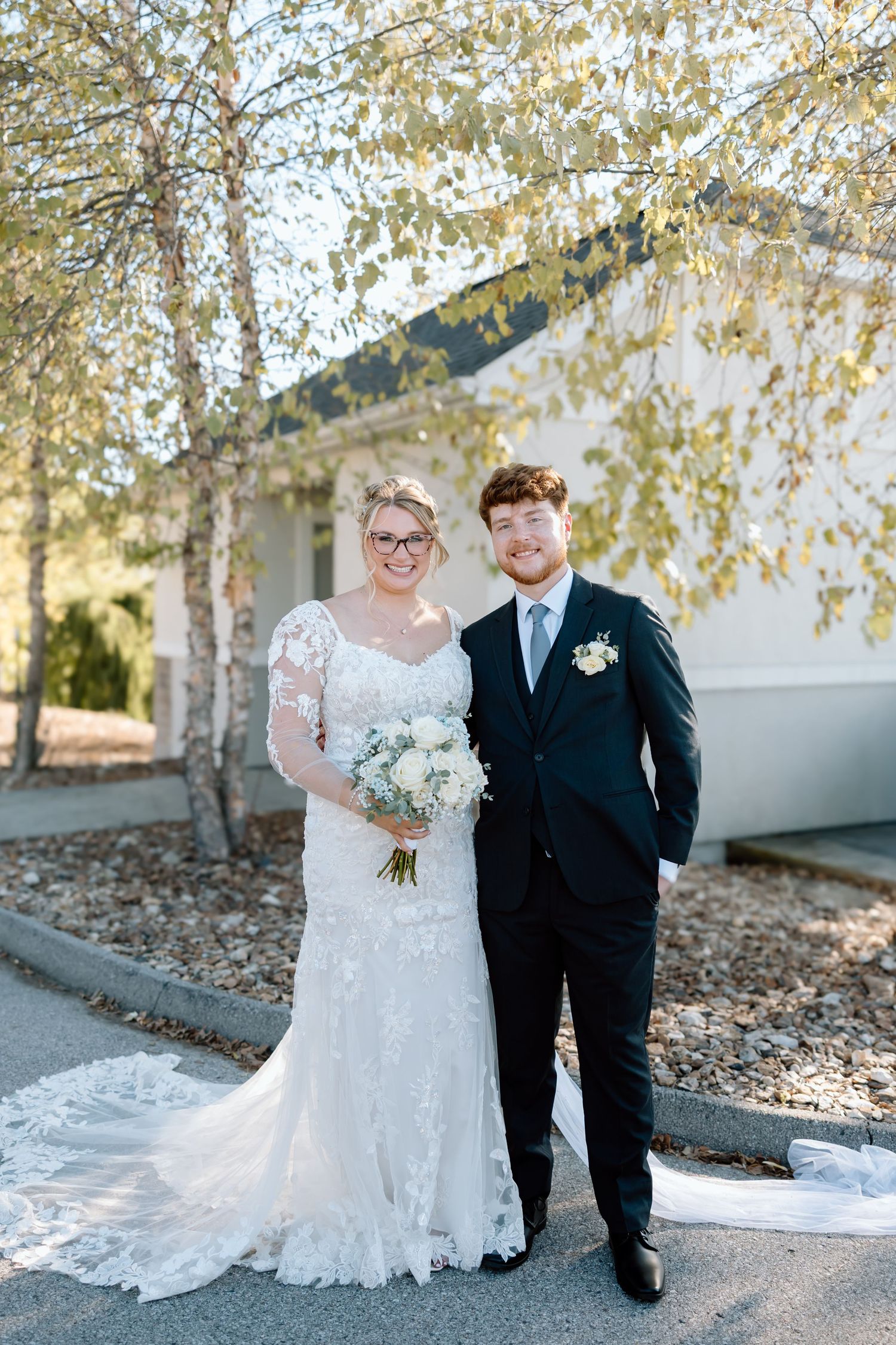A couple poses for wedding photos on a path lined with autumn birch trees.