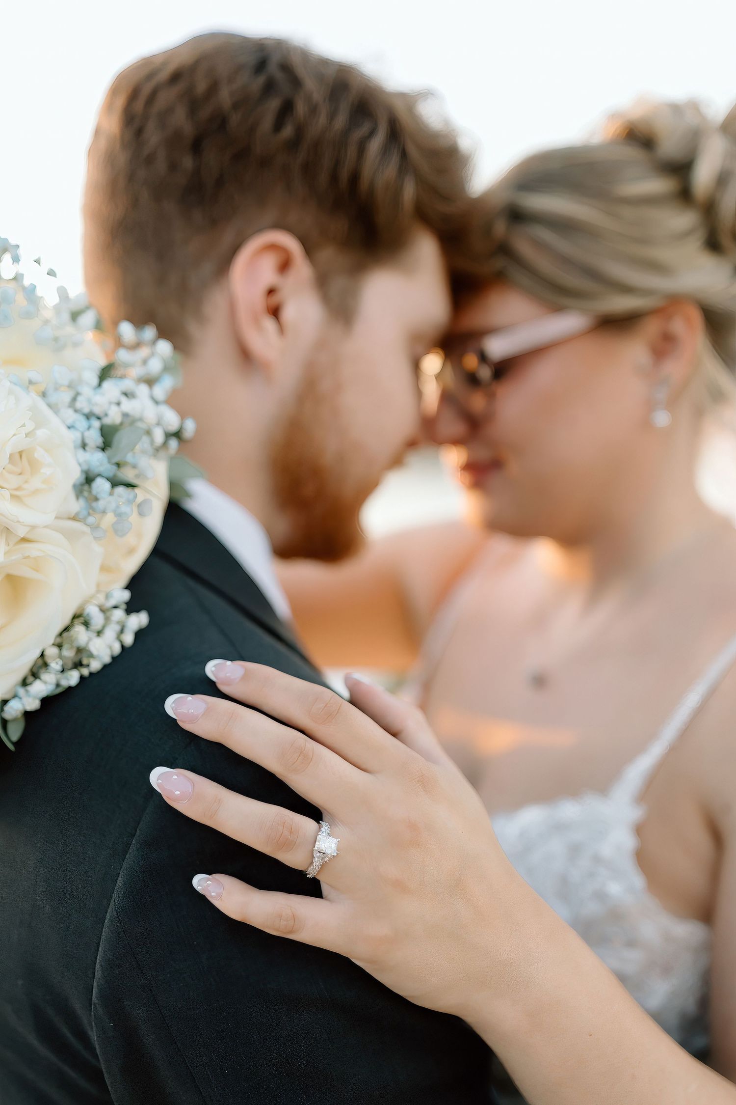 A romantic close-up of a couple sharing an intimate moment while showing off a sparkling engagement ring.