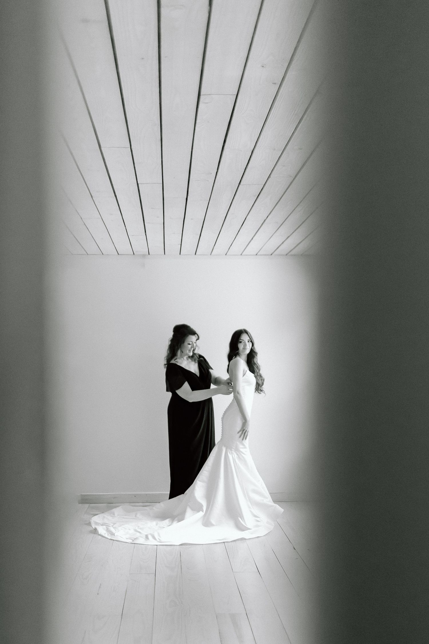 Two figures in contrasting black and white dresses create a striking silhouette against a minimalist white studio backdrop.
