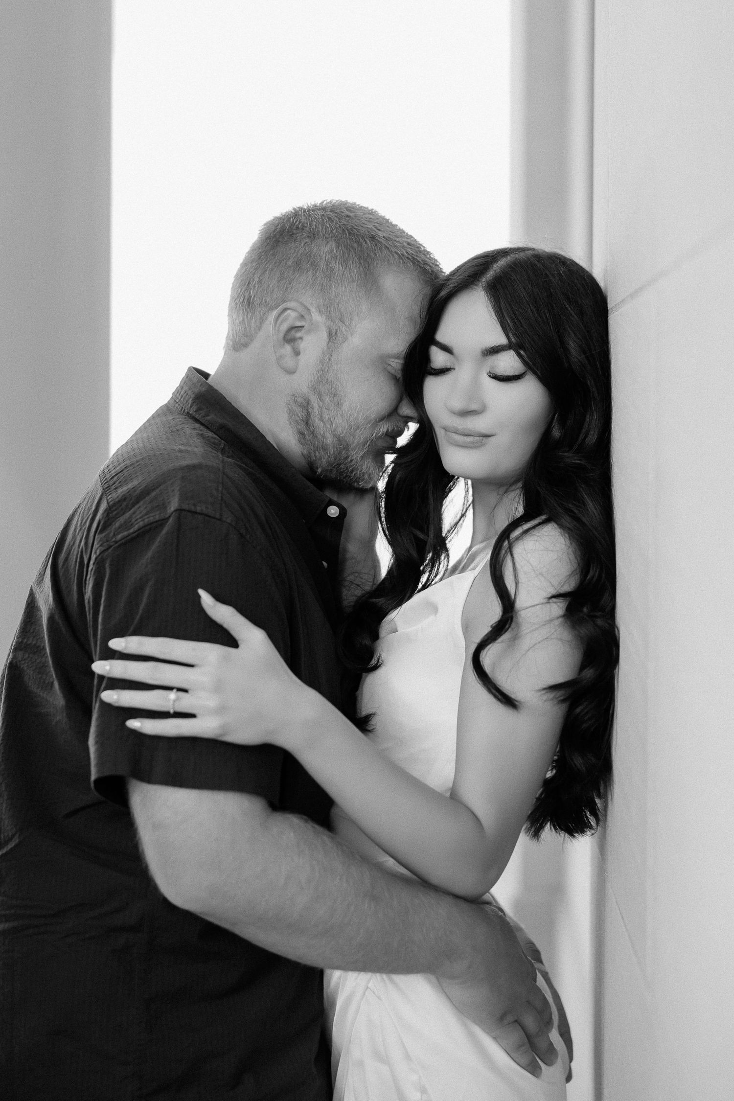 A romantic black and white photo sequence showing a couple embracing and kissing against a light background.