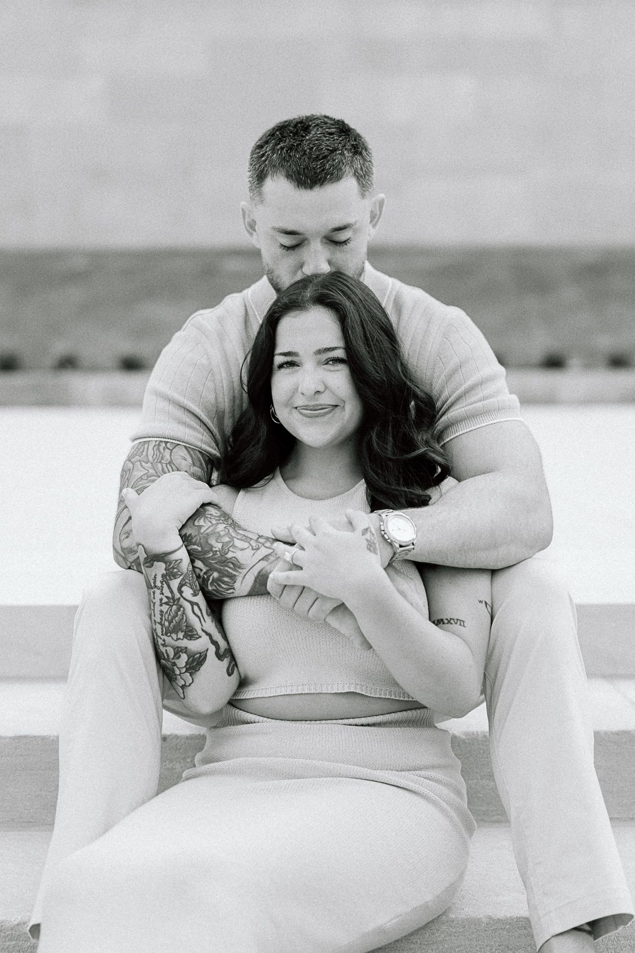 Intimate black and white maternity photos showing a couple embracing on a light background.