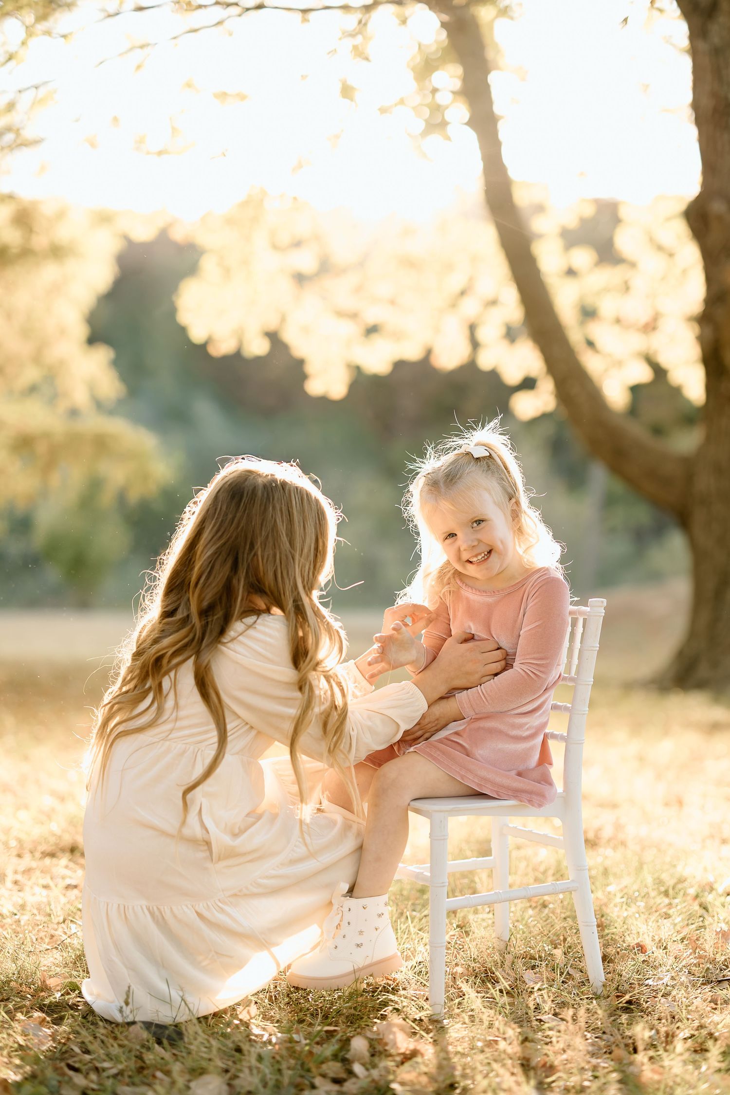 Sweet outdoor portrait in golden sunlight with white chair and soft pink and cream clothing.