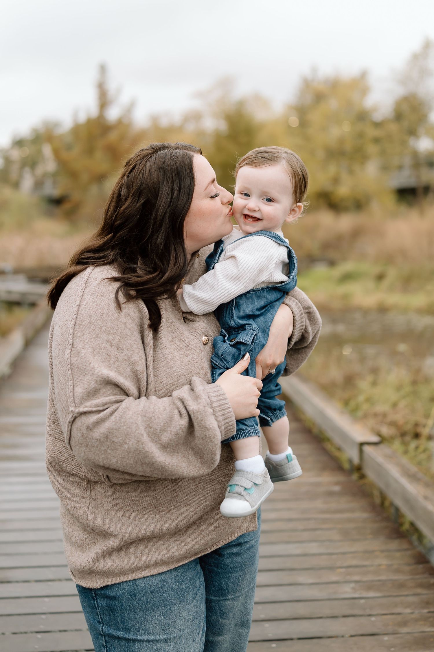 A series of tender moments captured on a wooden boardwalk showing affectionate interaction in warm autumn lighting.