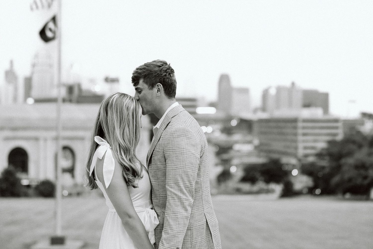 A romantic black and white photo of a couple embracing with a city skyline in the background.