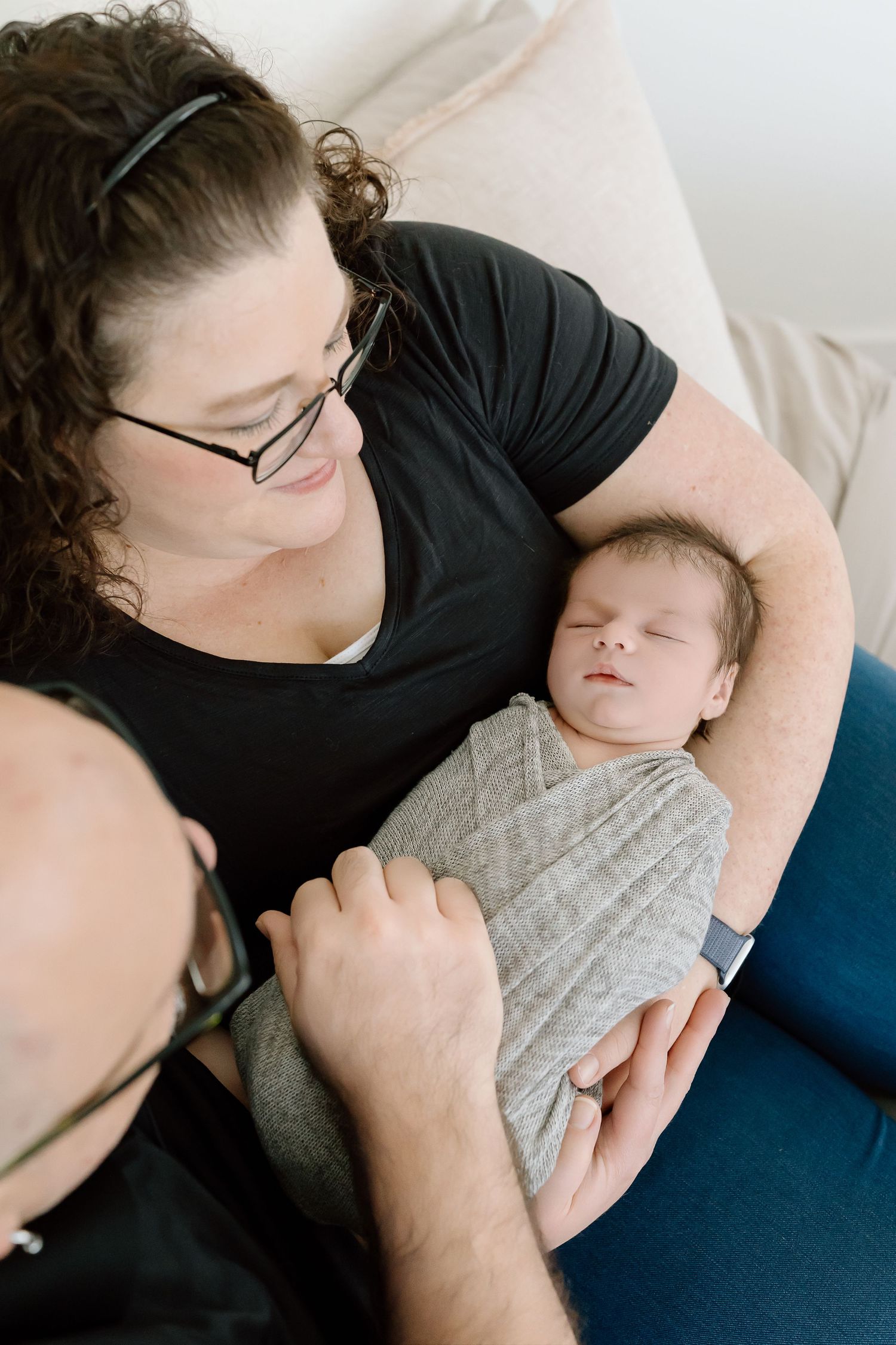 Tender moment of parent and baby resting together on blue couch.