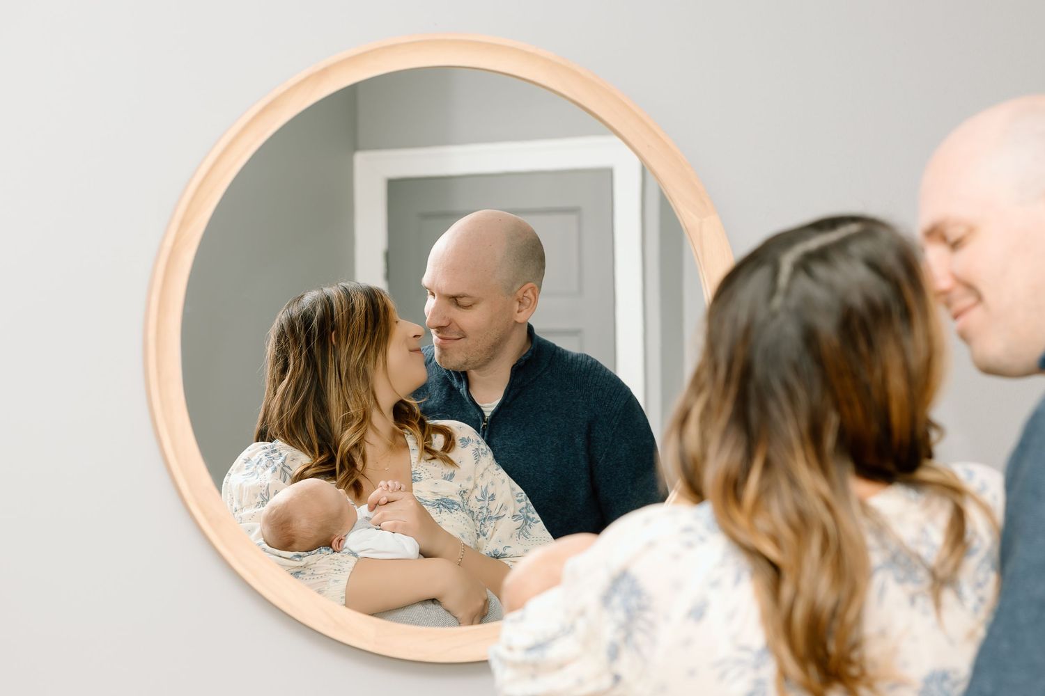 A series of five similar photos showing intimate family moments in a light-filled room with a mirror.