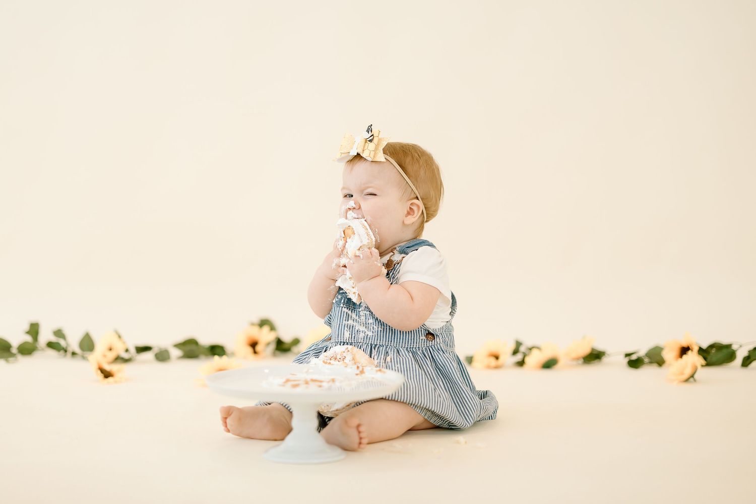 A series of four connected images showing a baby in a white dress crawling and playing on a light-colored backdrop.