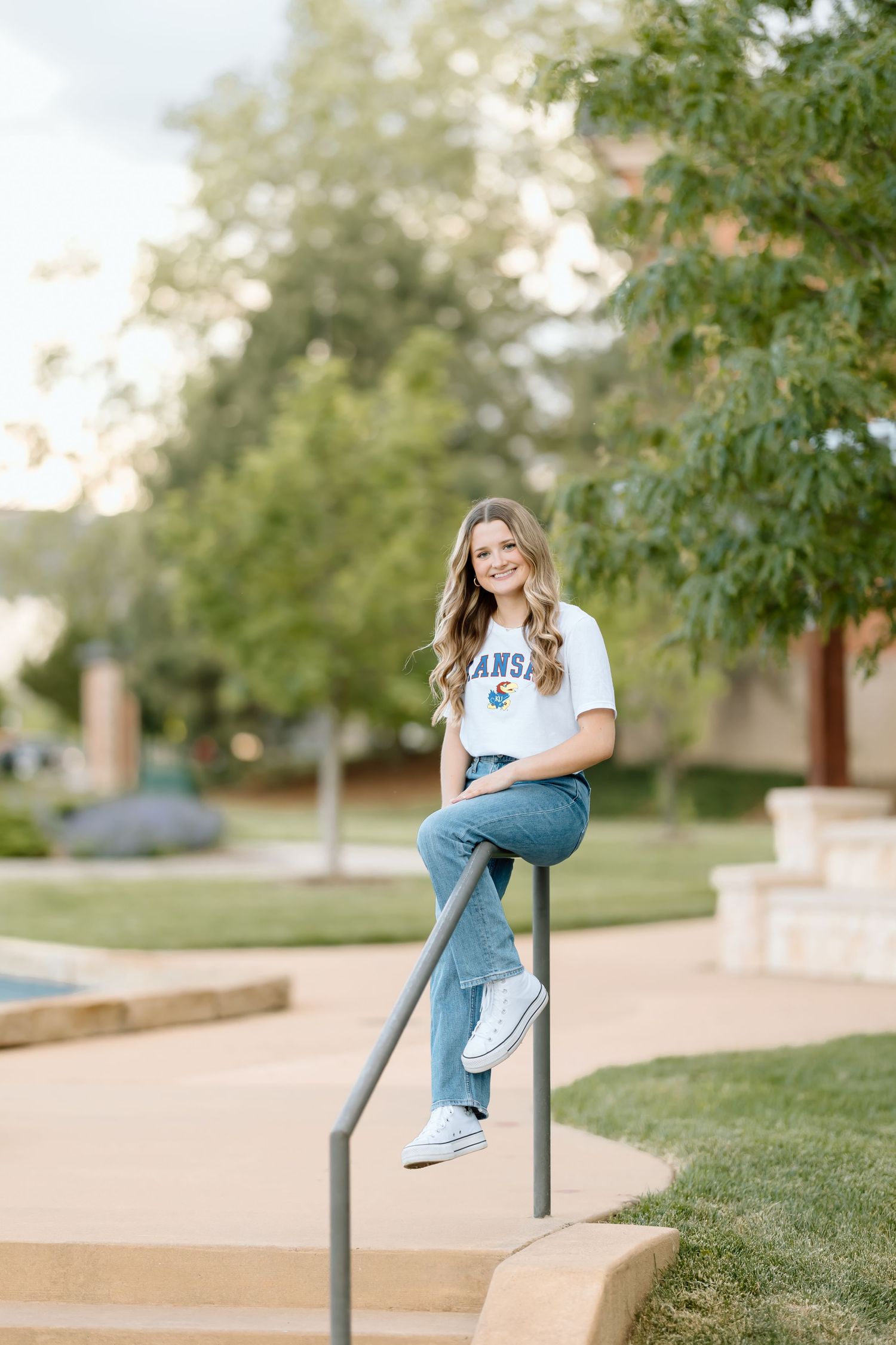 A casual lifestyle portrait series showing someone in jeans and white t-shirt sitting on a metal railing in a park setting.