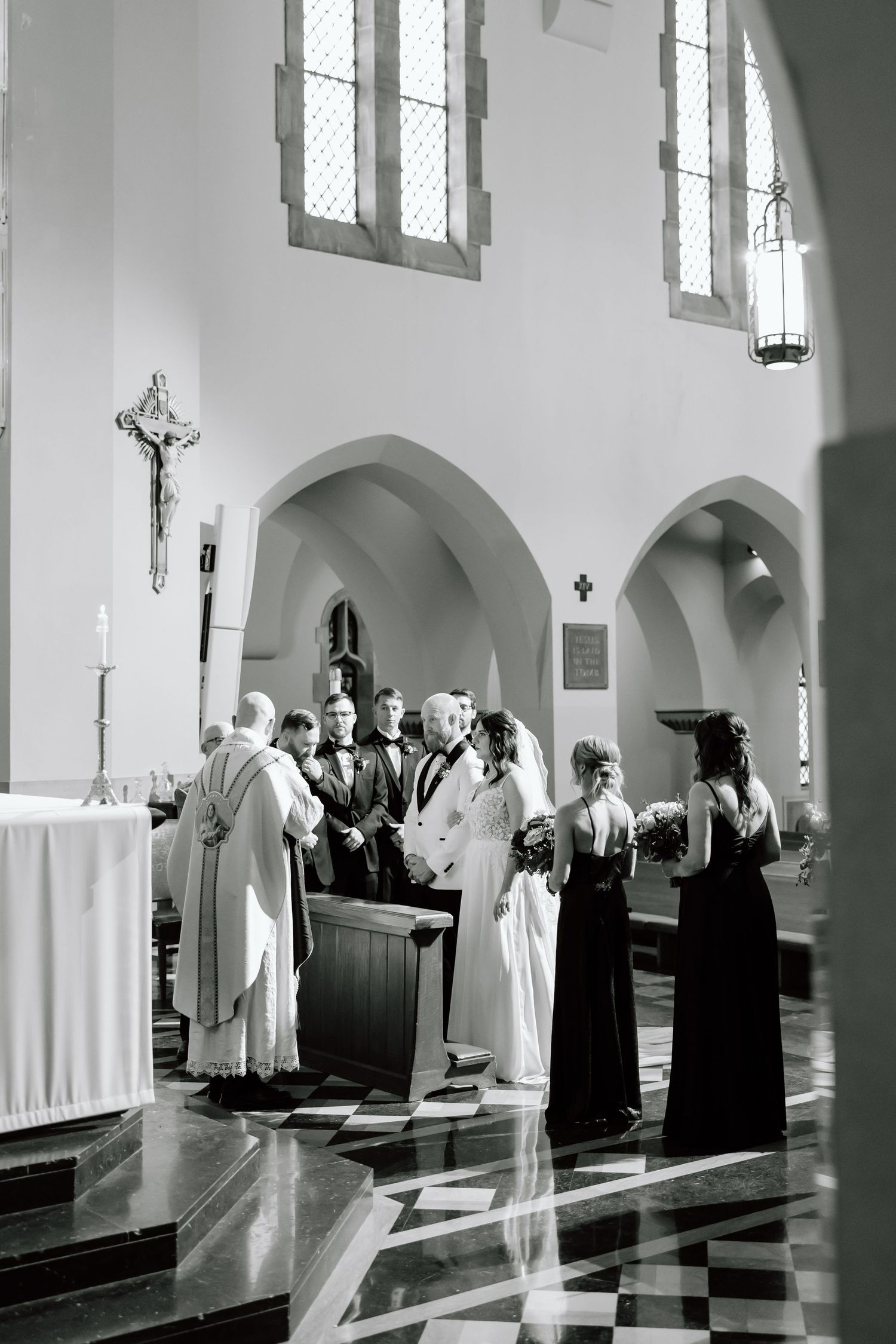 Black and white photograph of clergy members standing in a church sanctuary during a religious ceremony.